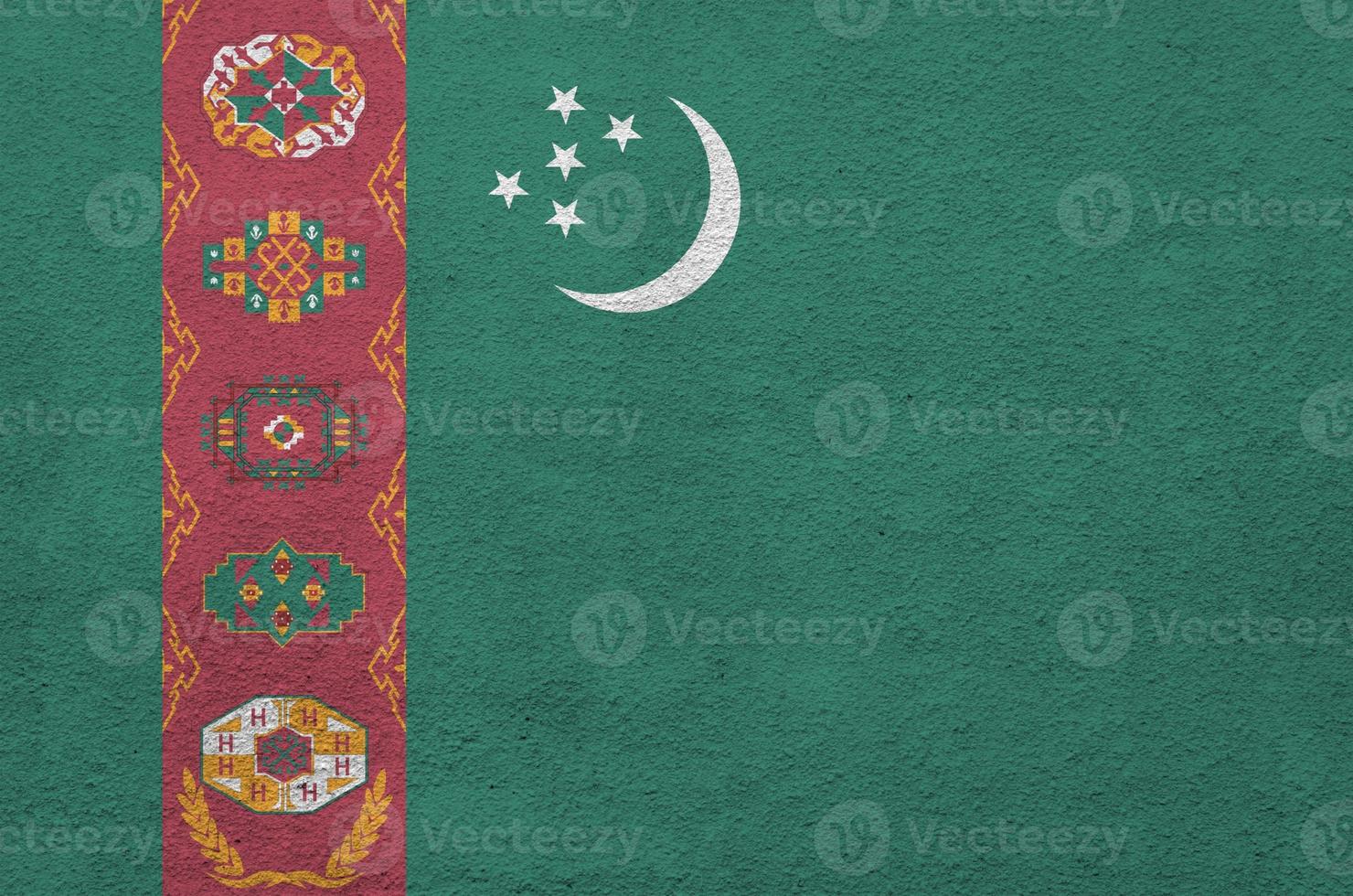 Turkmenistan flag depicted in bright paint colors on old relief plastering wall. Textured banner on rough background photo