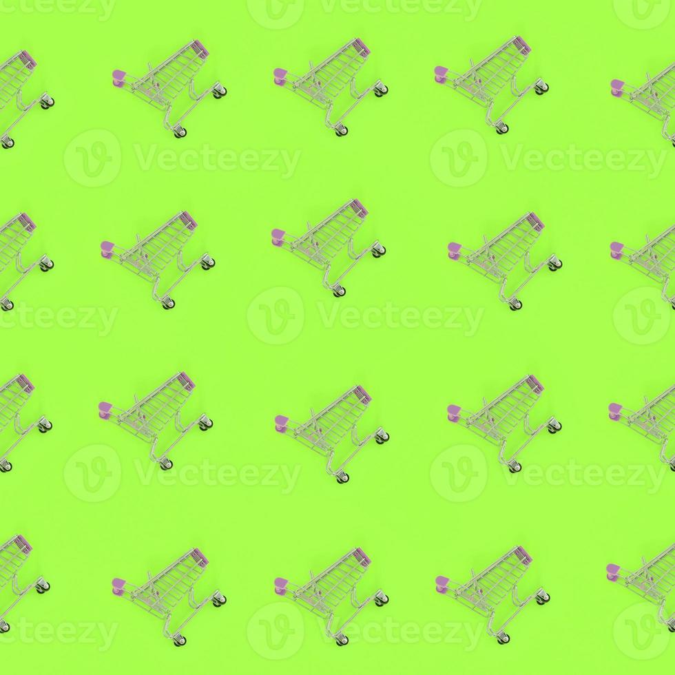 Shopping addiction, shopping lover or shopaholic concept. Many small empty shopping carts perform a pattern on a pastel colored paper background. Flat lay composition, top view photo
