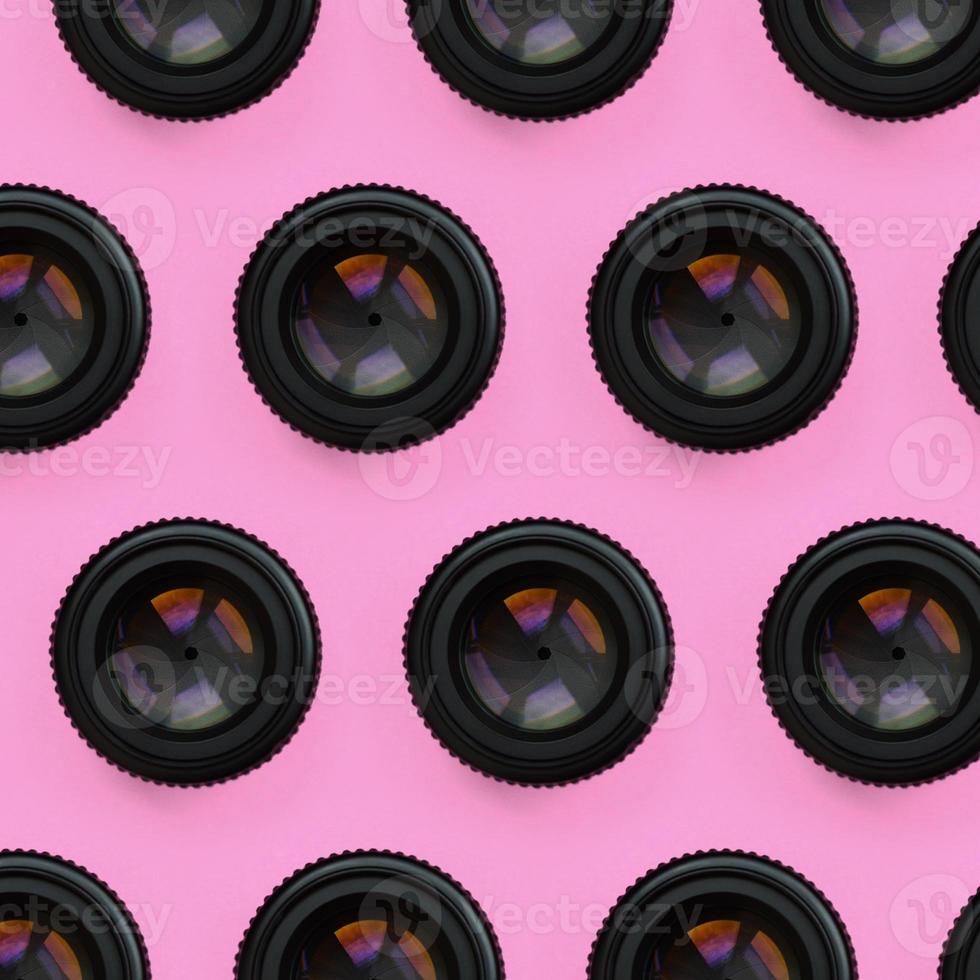 A few camera lenses with a closed aperture lie on texture background of fashion pastel pink color paper in minimal concept. Abstract trendy pattern photo