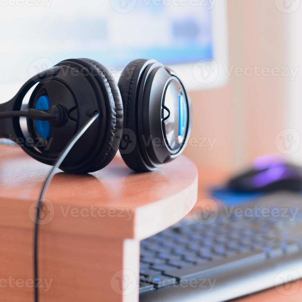 Big black headphones lie on the wooden desktop of the sound designer photo