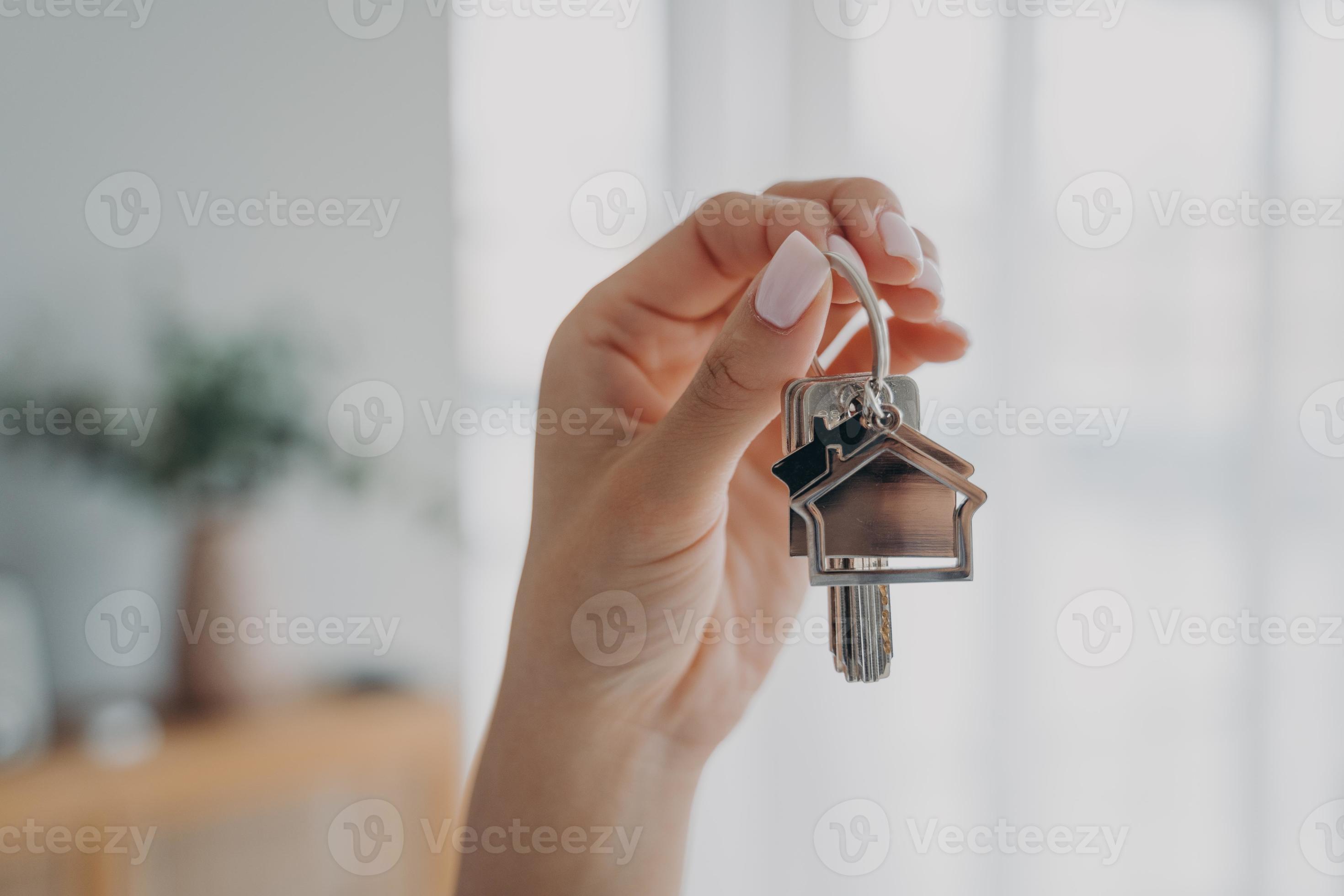 Key to new home. Close up female hand holding house keys. Real estate