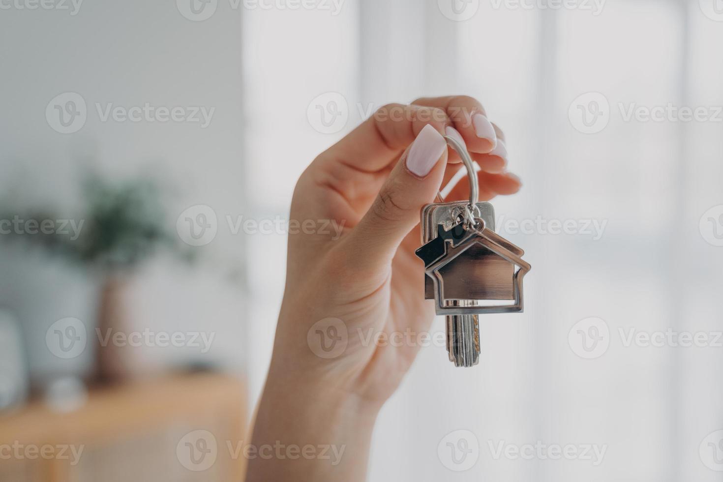 Key to new home. Close up female hand holding house keys. Real estate agent offers apartment photo