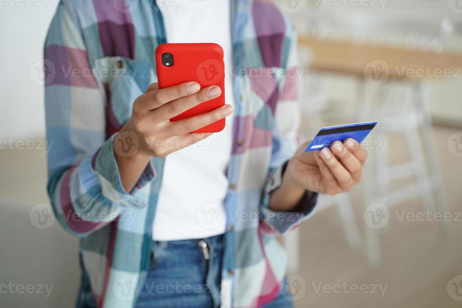 Female holding credit card, phone, uses online banking services, mobile bank apps, paying purchases photo