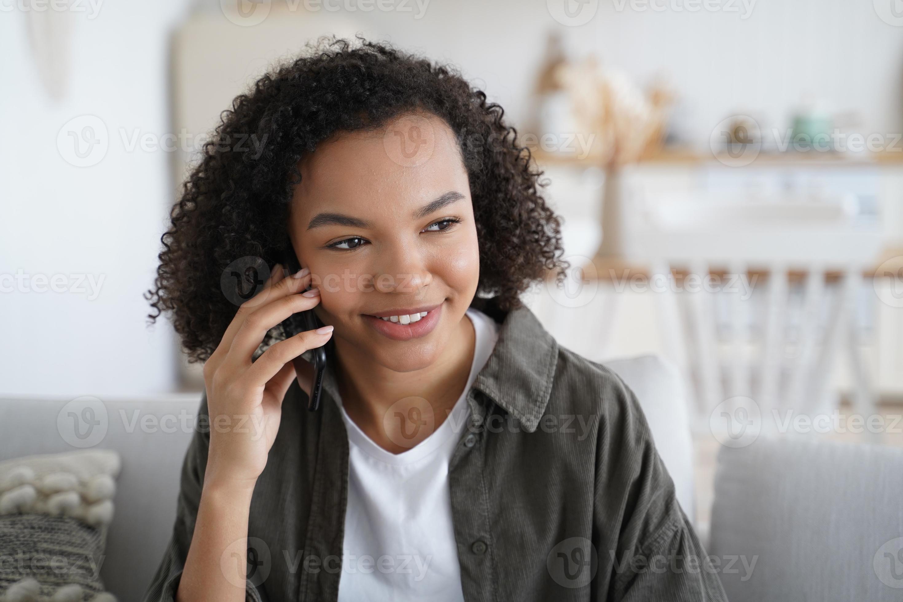 Amable y sonriente jovencita de raza mixta hace una llamada telefónica