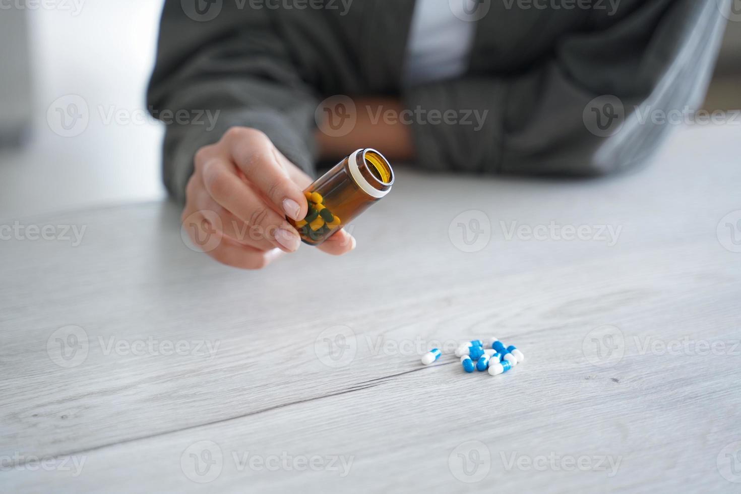 Female holds jar with medicines, pours pills on table, close up. Dietary supplement, vitamins, meds photo