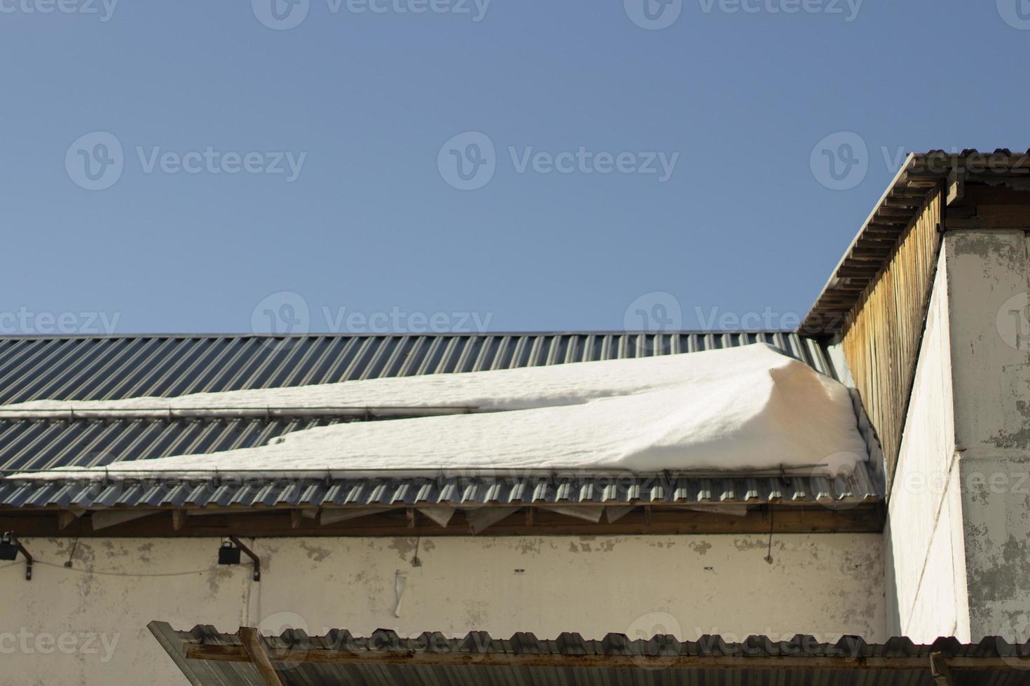 Snow on roof. Roof of building in winter. Architectural details. photo