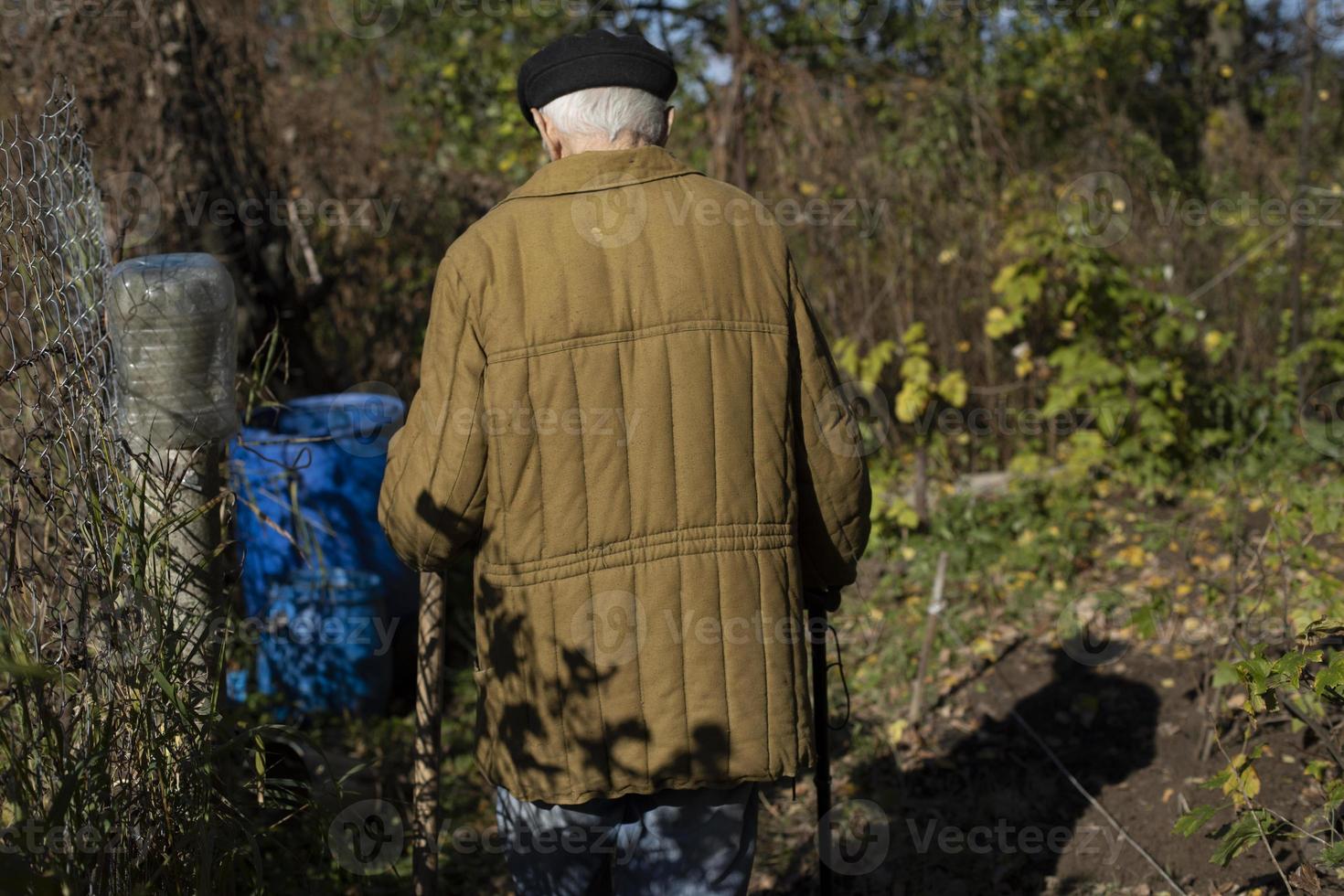 Old man at barrel of water. Old man in Russia. Man in 20th century military jacket. photo