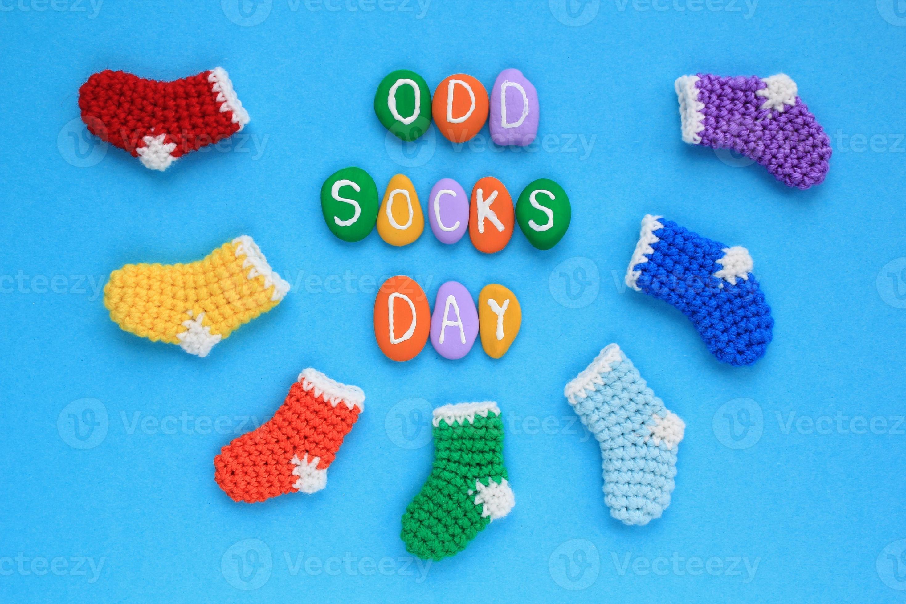 Odd socks day lettering and mismatched colourful socks on blue background. Social school