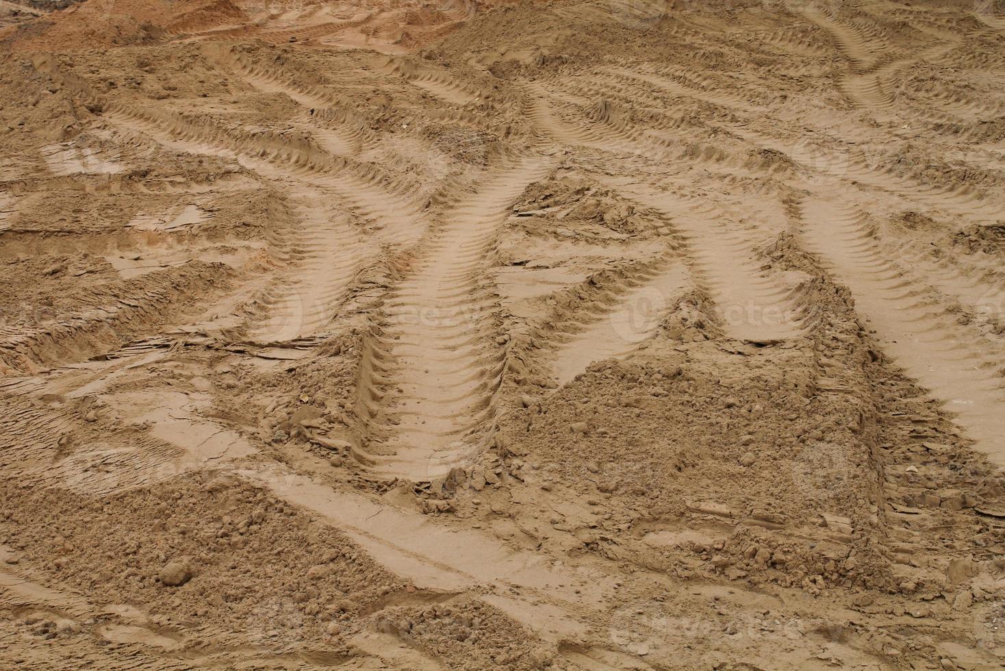 Tire track mark lines shape on dry sand background. Trail tyre imprint from heavy machinery. Vehicle shape. Road construction site backdrop concept. Trace of wheel pattern on mud. Nature texture. photo