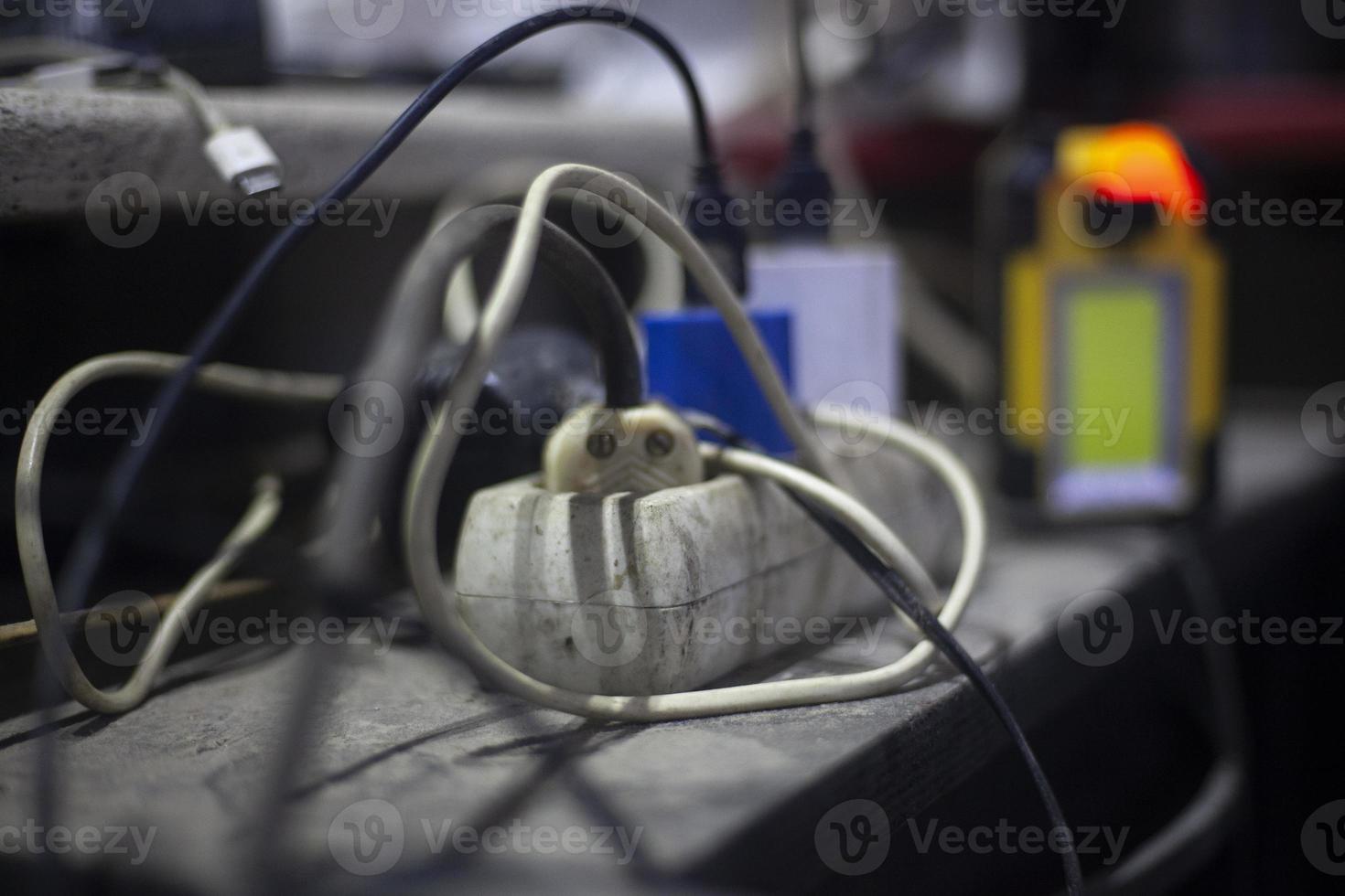 The charger is plugged in. Entangled wires from sockets of various devices. Chaos in home wired equipment. High voltage in the network. photo