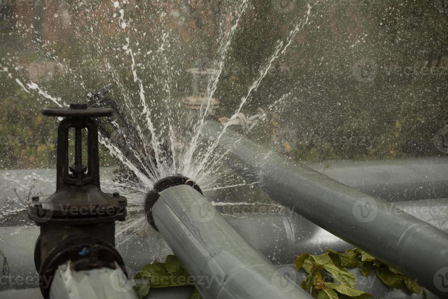 Valve on tube. Torn pipe valve. Boiling water pours from pipeline. photo