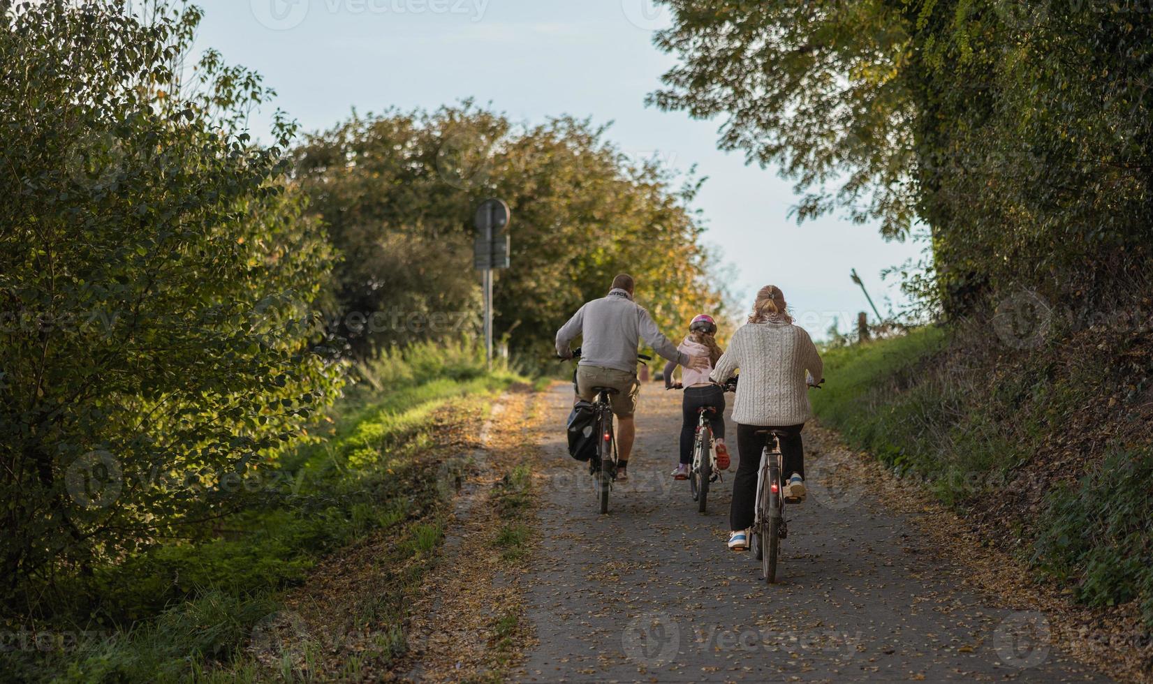 Family enjoying bike ride in park. Weekend bike riding. photo