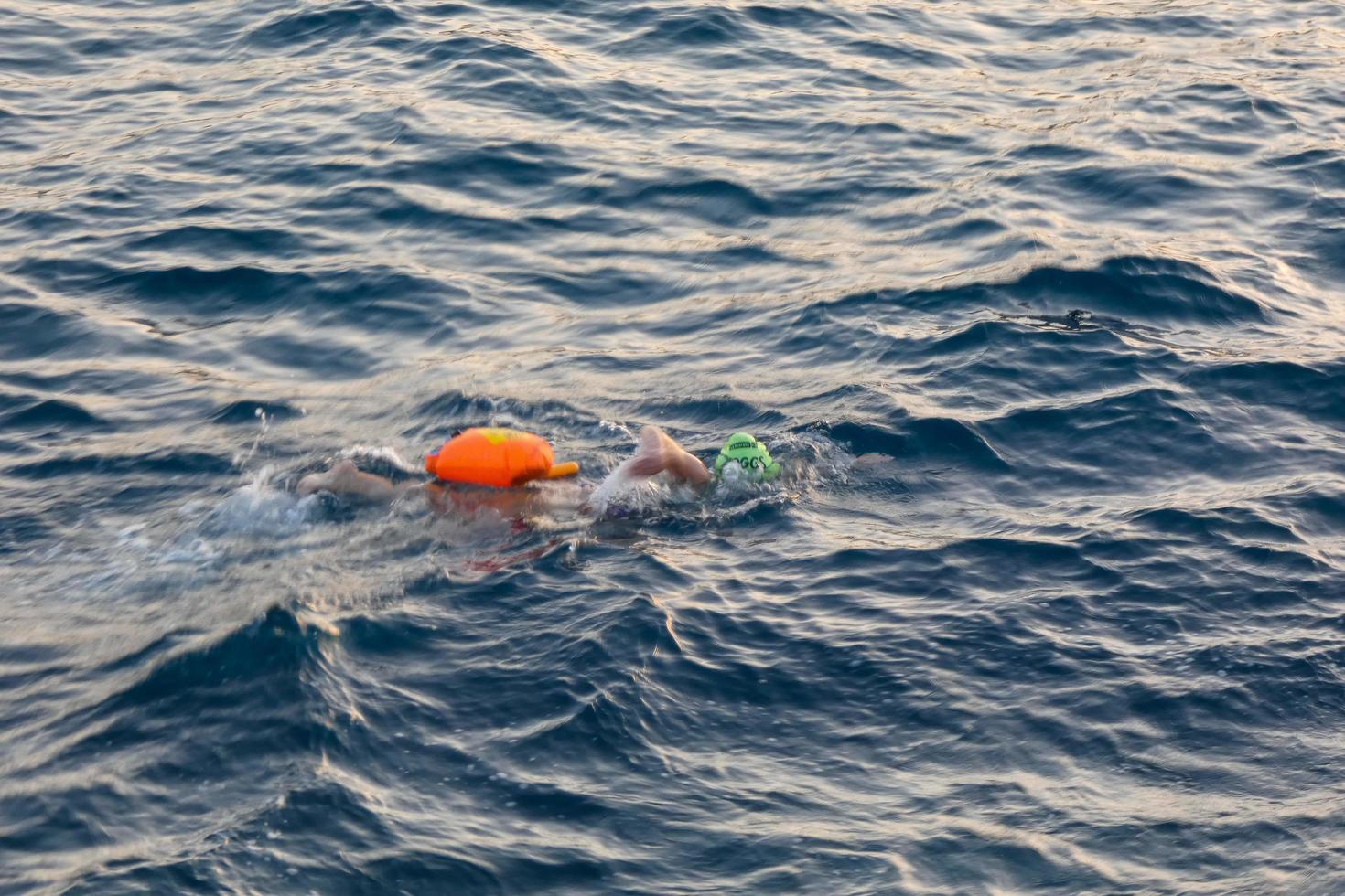 Swimmer swimming in open water in the Mediterranean Sea with a safety buoy photo