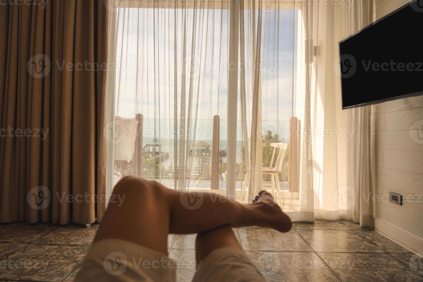 Man relaxing cross legged in bedroom with sunshine through curtain in the morning photo