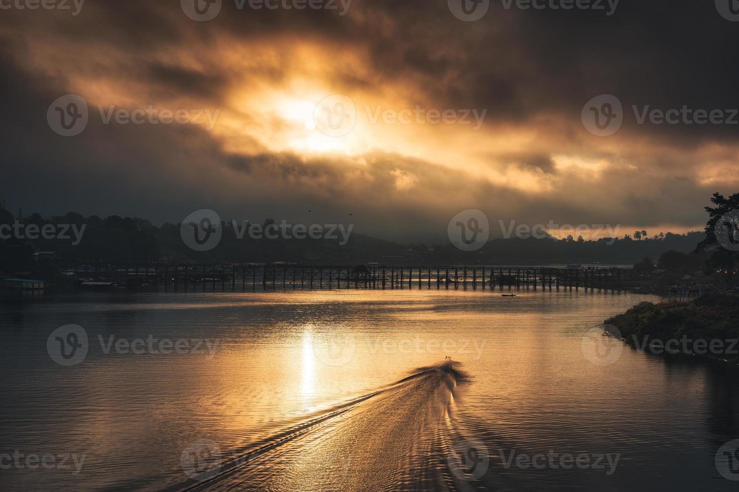 Sunrise over Mon wooden bridge and traditional boat on Songkalia river and Mon local village at Sangkhlaburi photo