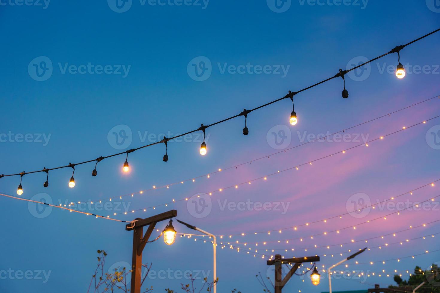 Retro light bulb glowing from string hanging decorative on celebration yard photo