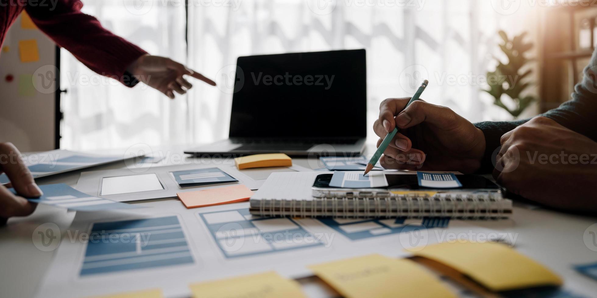 Close up ux developer and ui designer brainstorming about mobile app interface wireframe design on table with customer breif and color code at modern office.Creative digital development agency photo