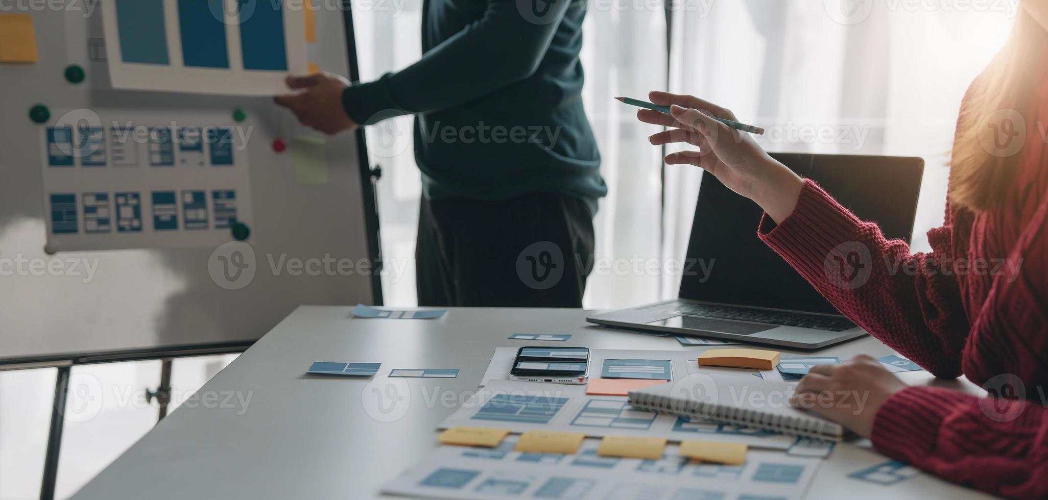 Ux developer and ui designer brainstorming about mobile app interface wireframe design on table with customer breif and color code at modern office.Creative digital development agency photo