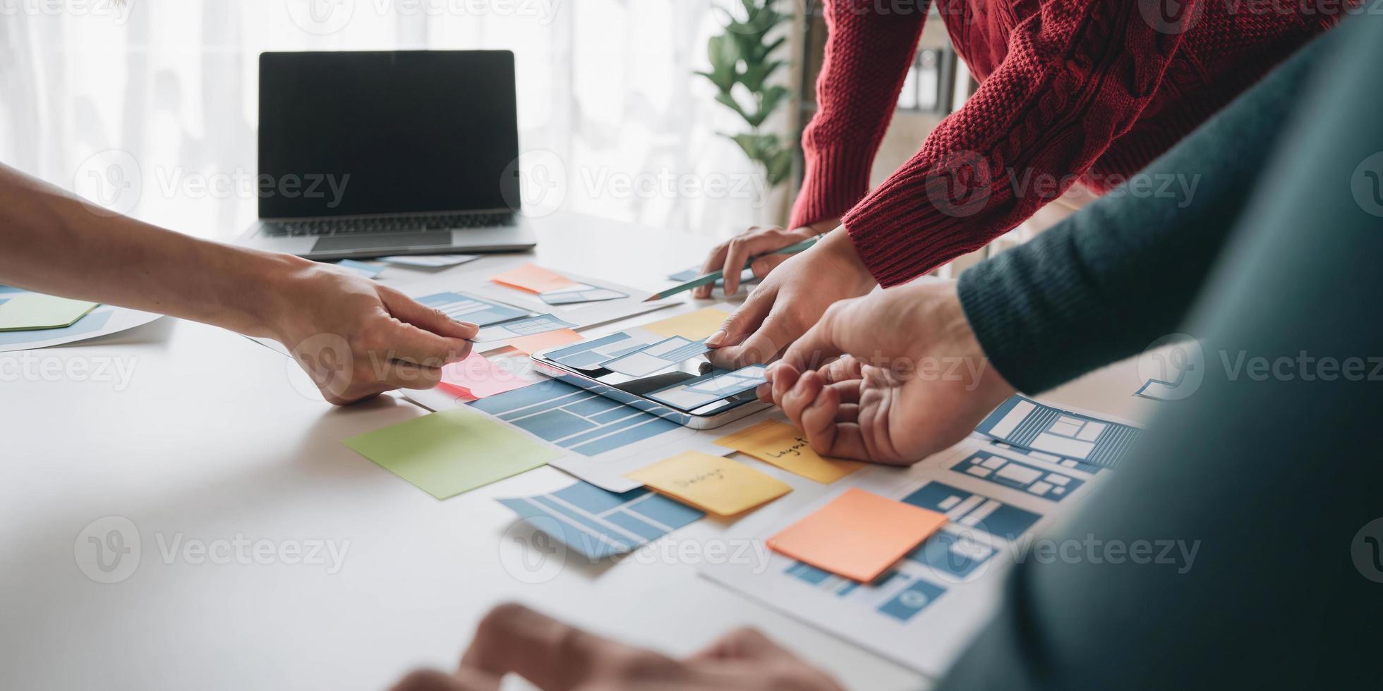 Close up ux developer and ui designer brainstorming about mobile app interface wireframe design on table with customer breif and color code at modern office.Creative digital development agency photo