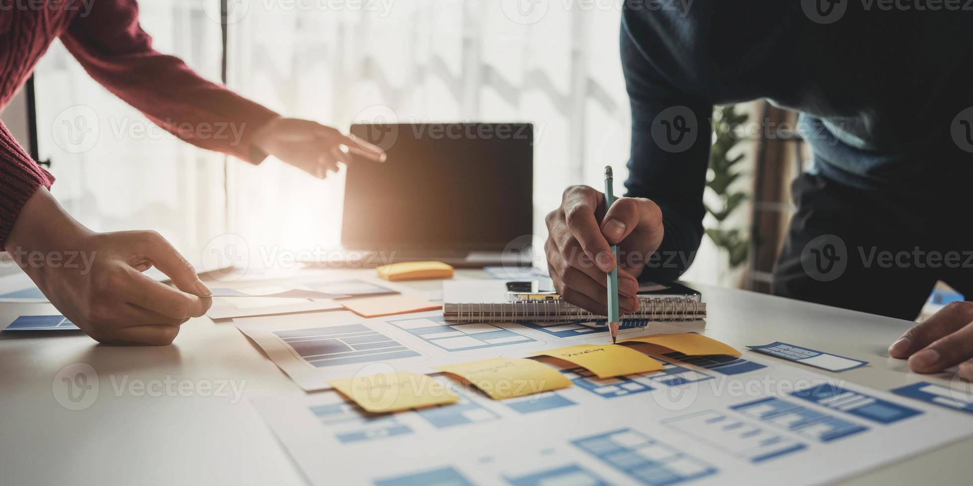 Ux developer and ui designer brainstorming about mobile app interface wireframe design on table with customer breif and color code at modern office.Creative digital development agency photo