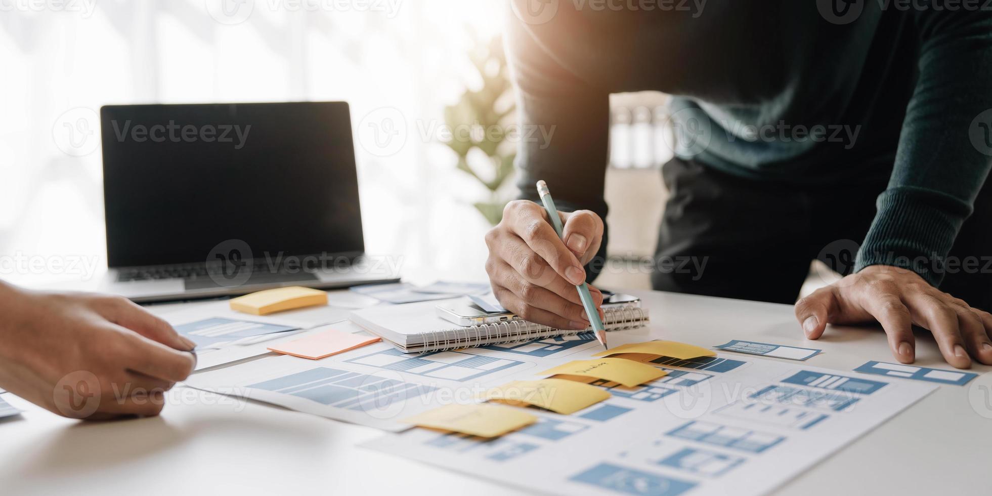 Ux developer and ui designer brainstorming about mobile app interface wireframe design on table with customer breif and color code at modern office.Creative digital development agency photo