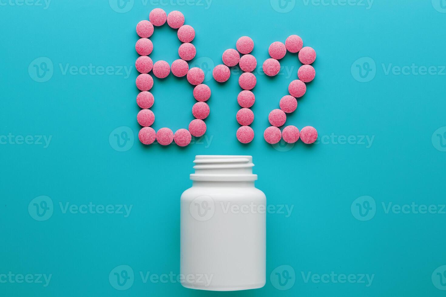 Pink pills in the shape of the letter B12 on a blue background, spilled