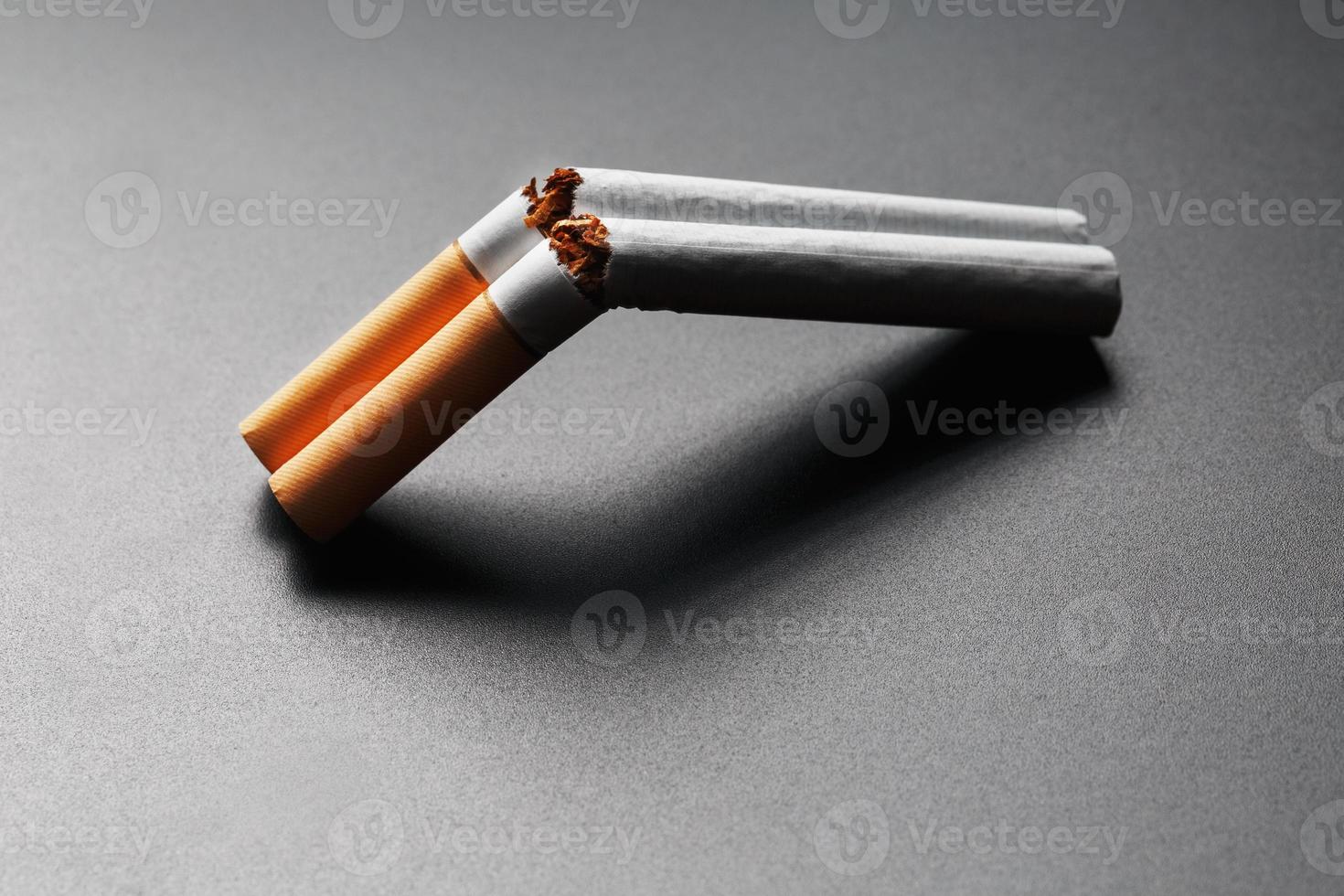 Two cigarettes in the form of a double-barreled shotgun on a black background with copy space. Stop smoking. The concept of smoking kills. photo