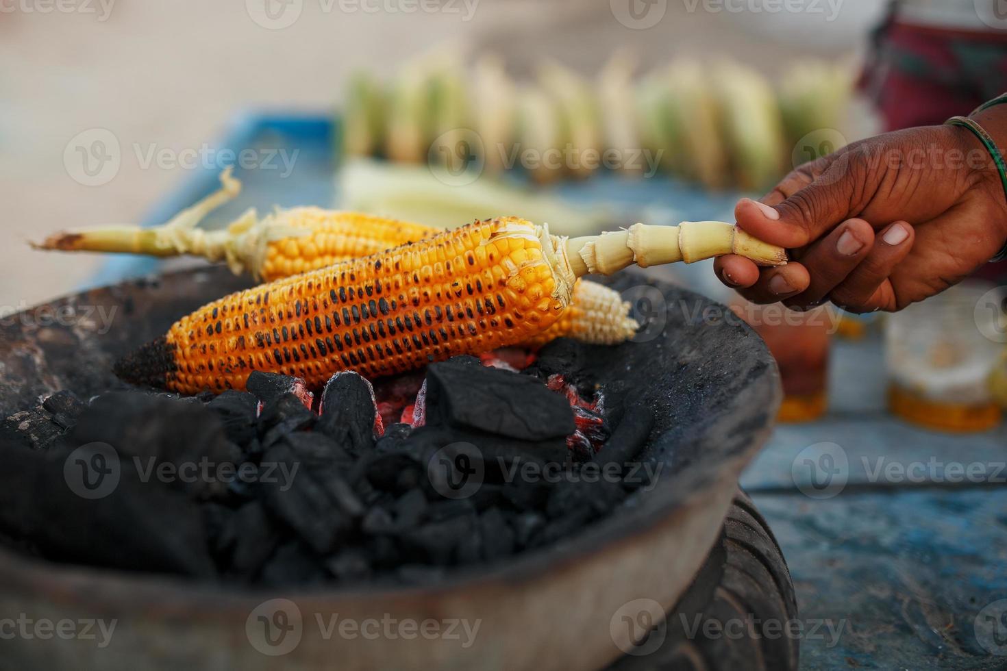 las manos cercanas de una vendedora ambulante están frotando una mazorca de maíz dulce asada con limón y especias. concepto de comida callejera india, primer plano foto