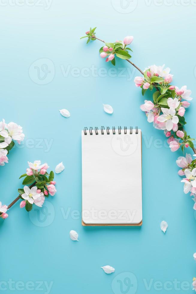 Blooming spring sakura on a blue background with notepad space for a greeting message. The concept of spring and mother's day. Beautiful delicate pink cherry flowers in springtime photo