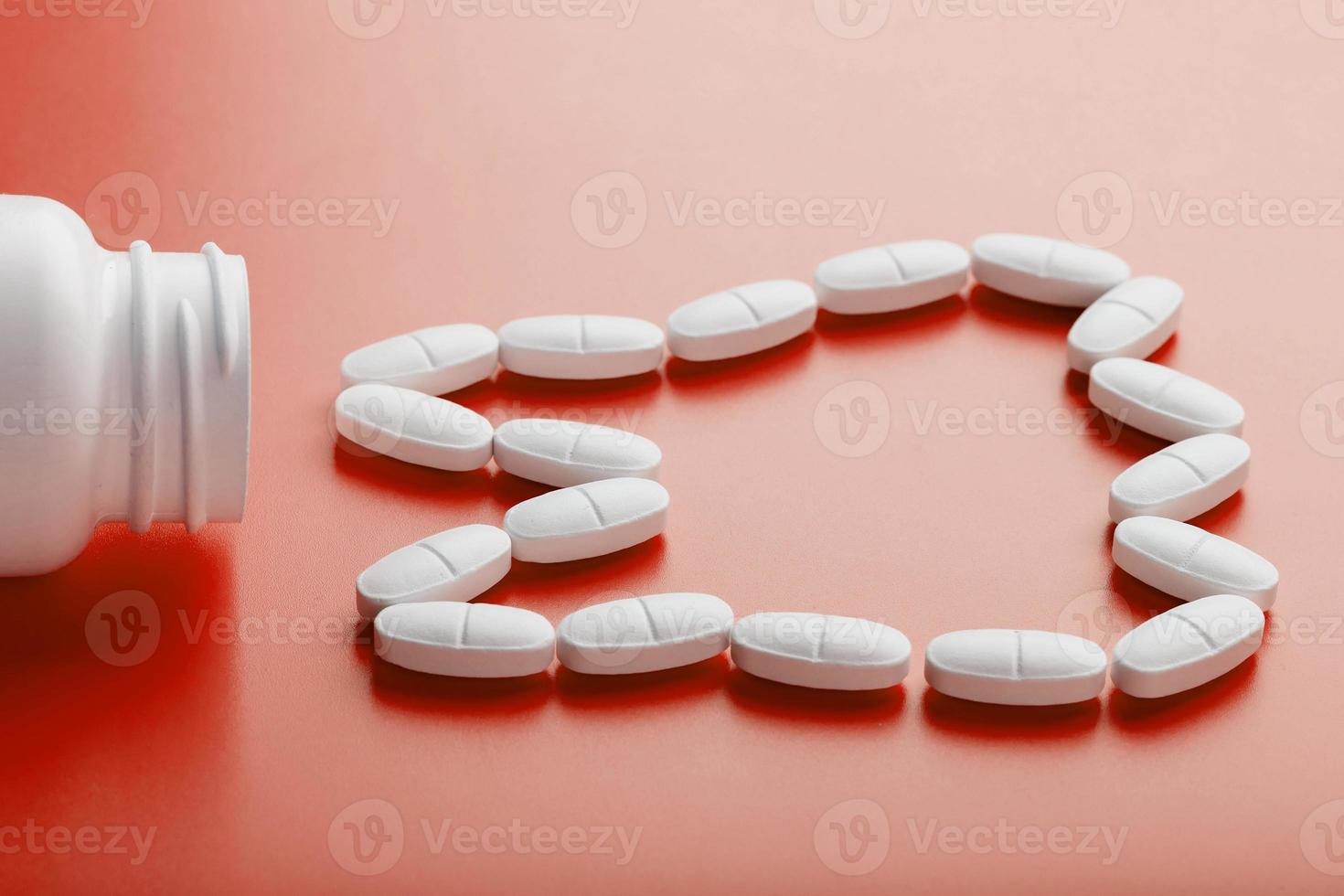 Calcium vitamin in the form of a tooth spilled out of a white jar on a red background. photo