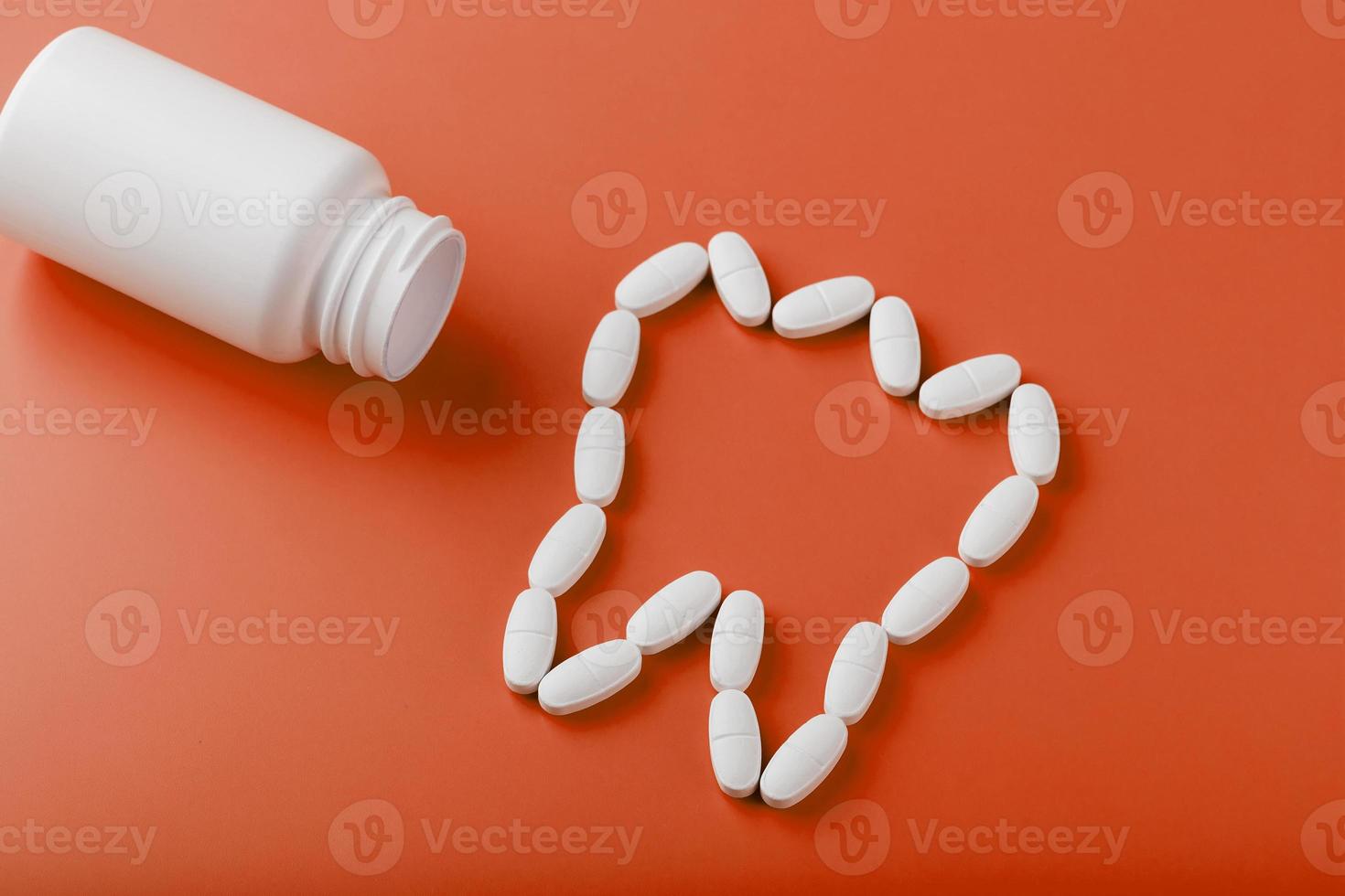 Calcium vitamin in the form of a tooth spilled out of a white jar on a red background. photo