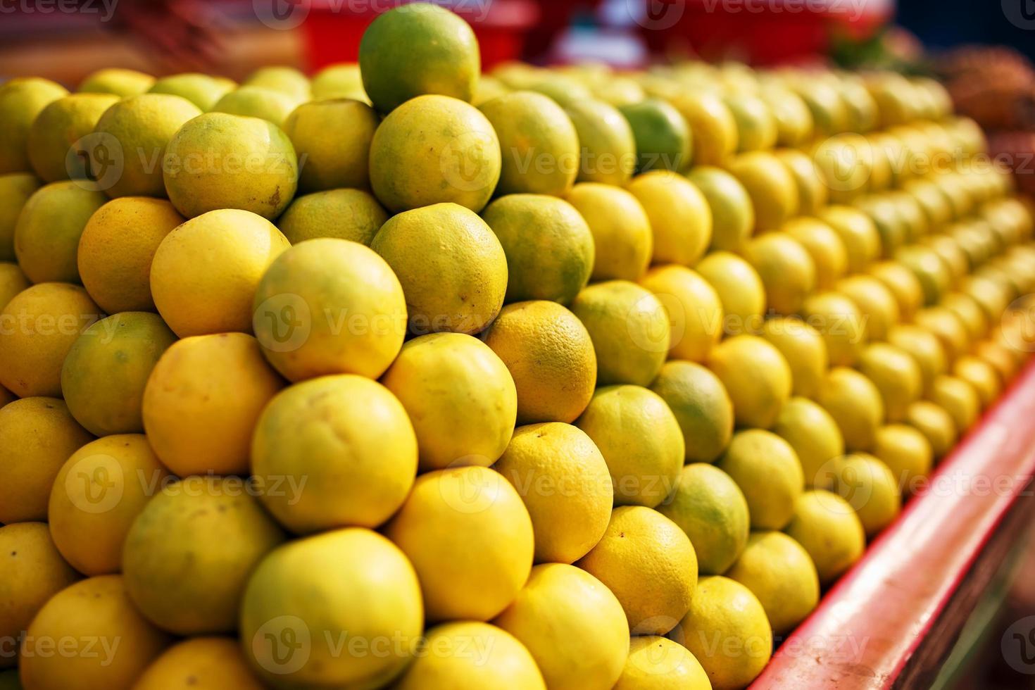 una pila de líneas amarillas maduras y dulces en toda la pantalla del mercado. fondo de lima y limones. limones y limas orgánicos frescos en un agricultor local foto