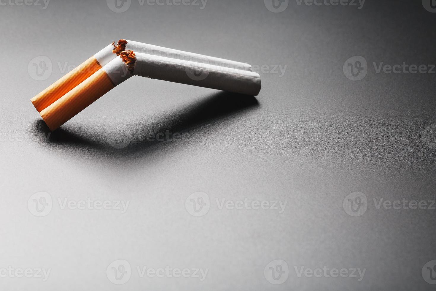 Two cigarettes in the form of a double-barreled shotgun on a black background with copy space. Stop smoking. The concept of smoking kills. photo