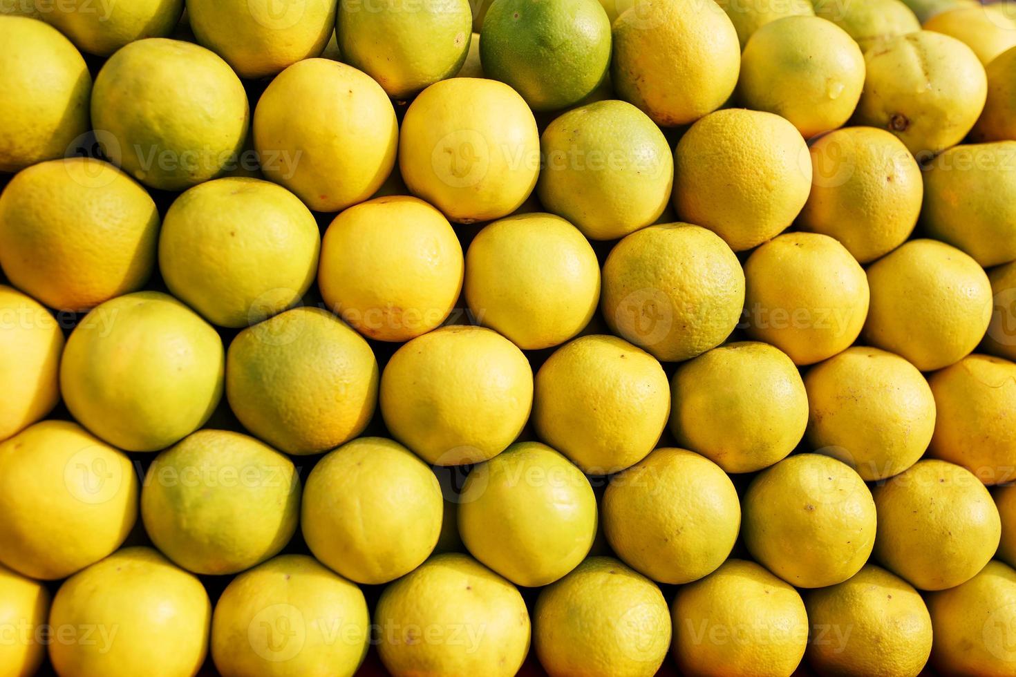 una pila de líneas amarillas maduras y dulces en toda la pantalla del mercado. fondo de lima y limones. limones y limas orgánicos frescos en un agricultor local foto