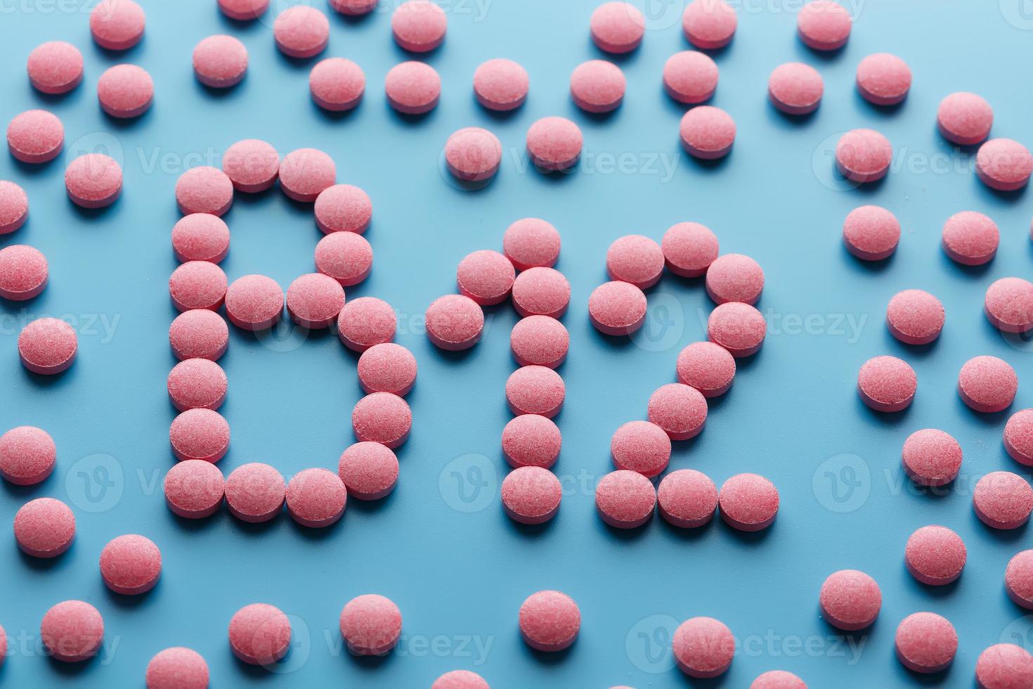 Pink tablets in the form of B12 in the heart on a blue background, spilled from a white can. photo