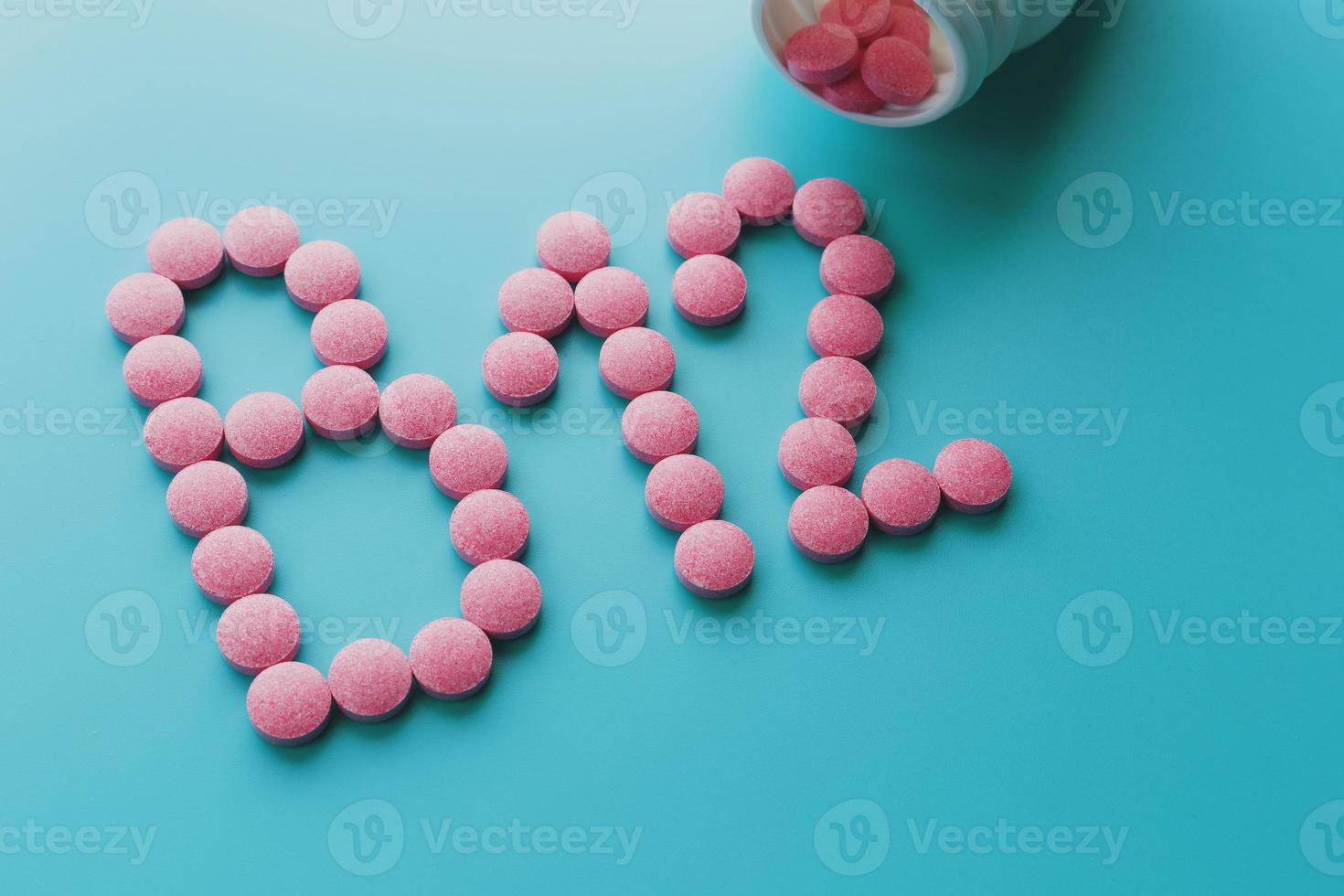 Pink tablets in the form of B12 close-up on a blue background from a white can, low contrast photo
