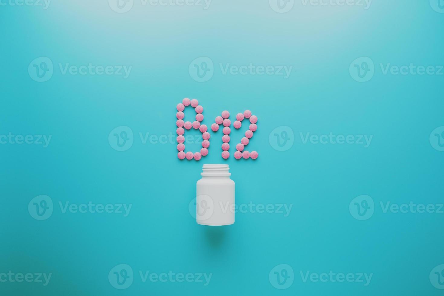 Pink pills in the shape of the letter B12 on a blue background, spilled out of a white can, low contrast photo