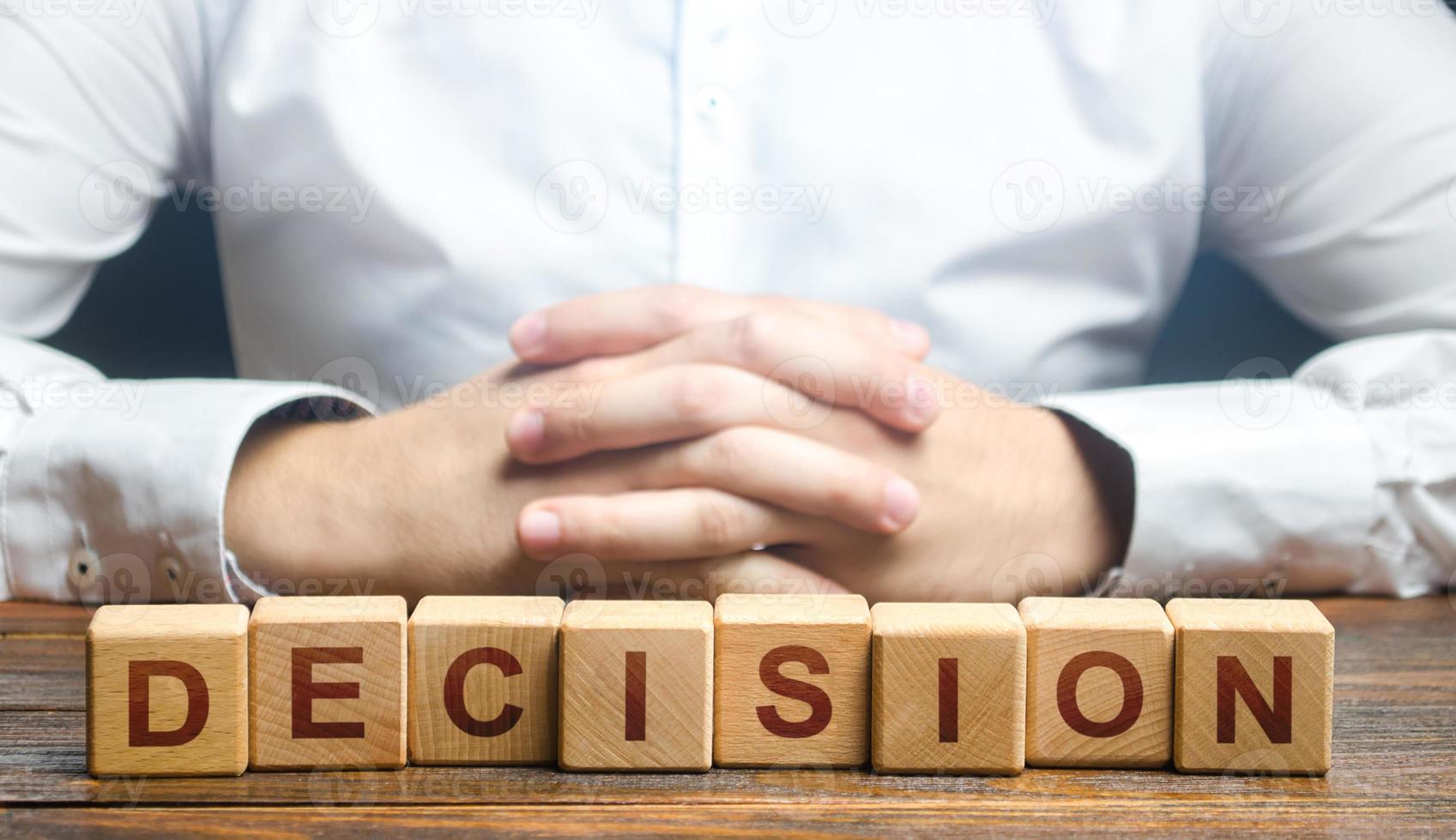 Man folded his hands on a background of blocks with the word Decision. Make the right decision, the answer to the question. Reasoning, weighing results and consequences. Authoritative opinion. photo