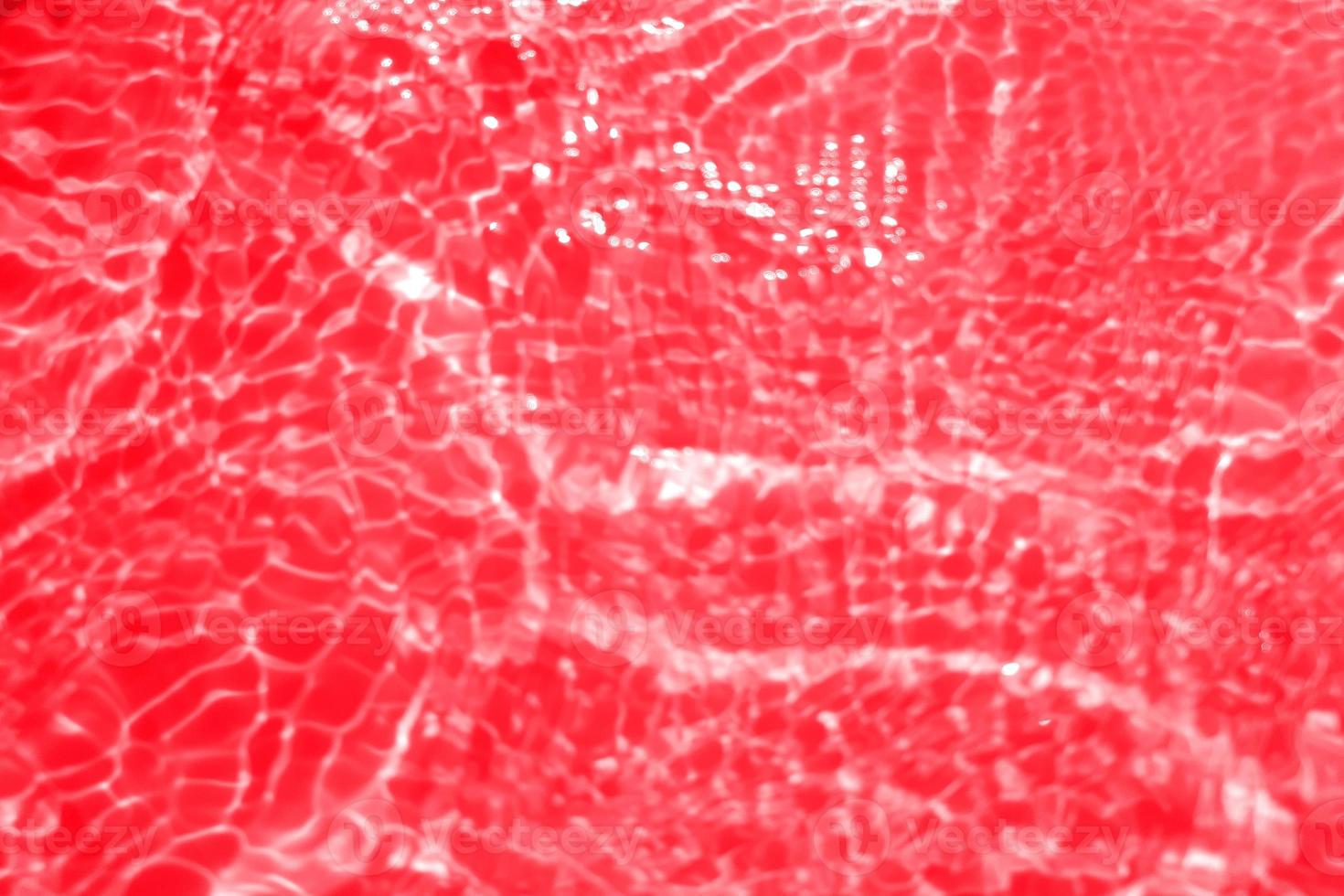 Defocus blurred transparent red colored clear calm water surface texture with splashes and bubbles. Trendy abstract nature background. Water waves in sunlight with copy space. Red watercolor shining photo