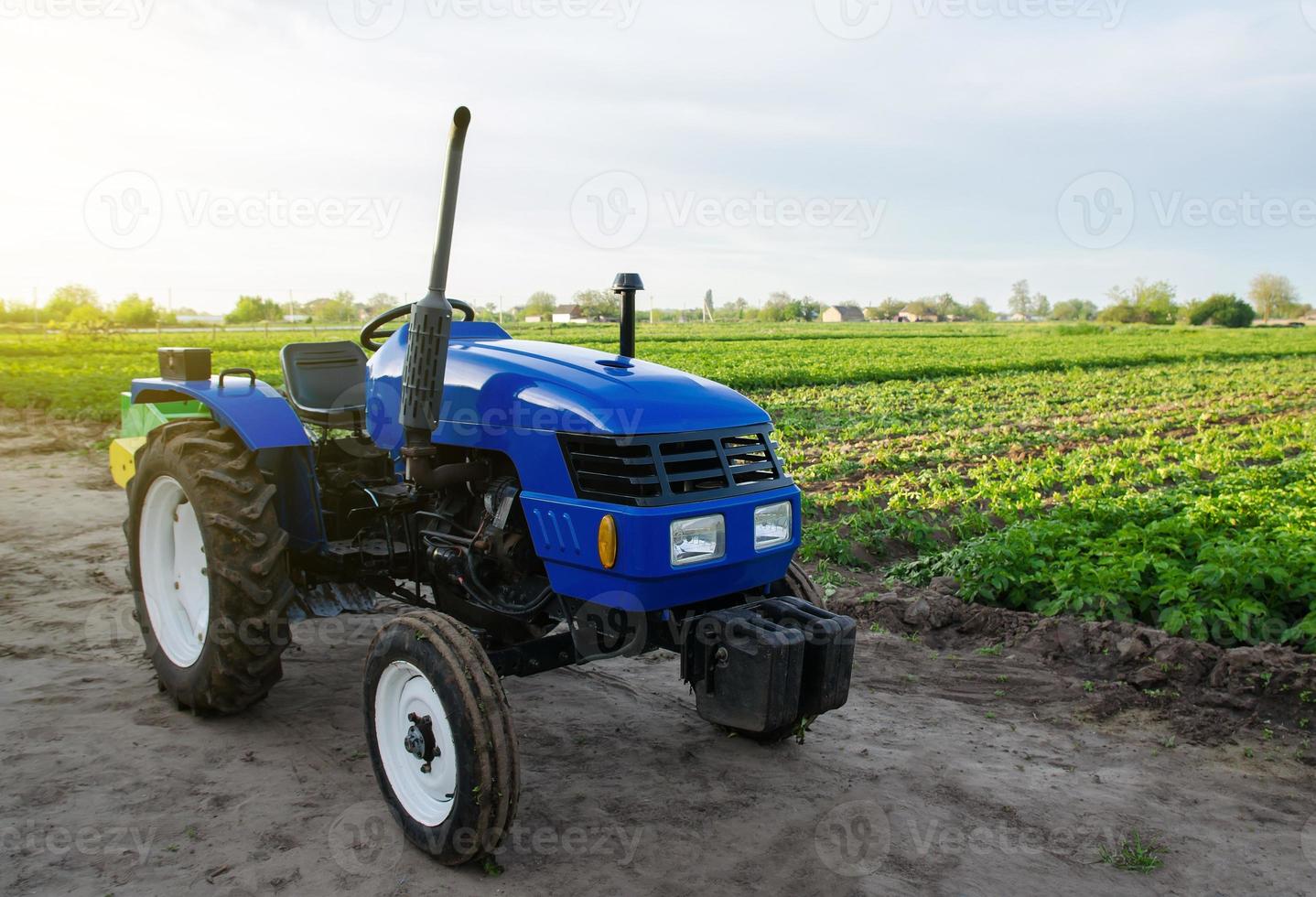 el tractor agrícola azul se encuentra en el campo. aplicación de maquinaria agrícola en la cosecha. modernización y automatización de procesos agrícolas. subvenciones y devoluciones de impuestos para la compra de nuevos equipos de trabajo foto