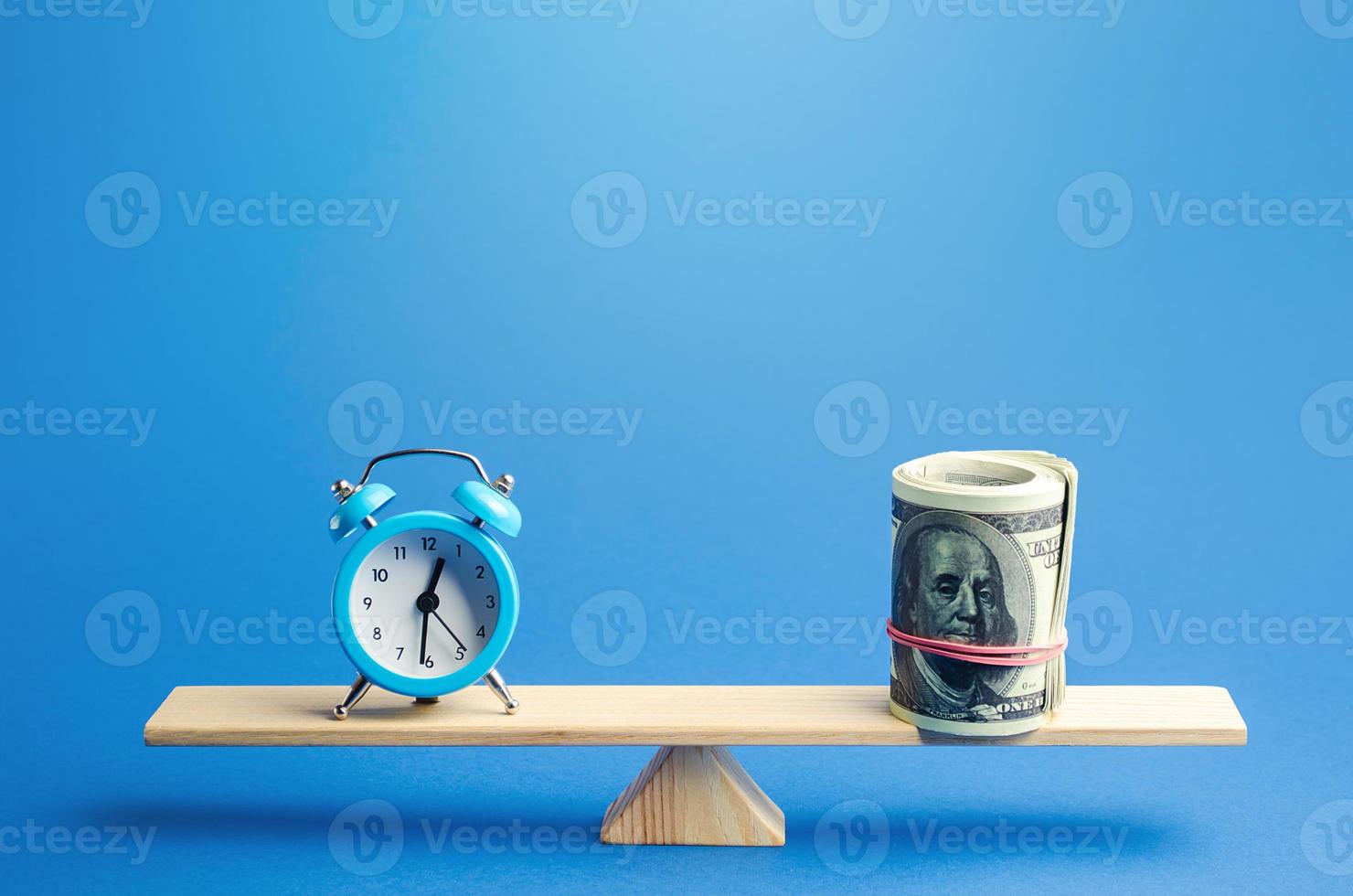Blue alarm clock and a bundle of dollars on scales. Fair hourly wages. Time tracking. Deposit, money investment. Profitability and return on investment. Rental. Balance between life and career. photo