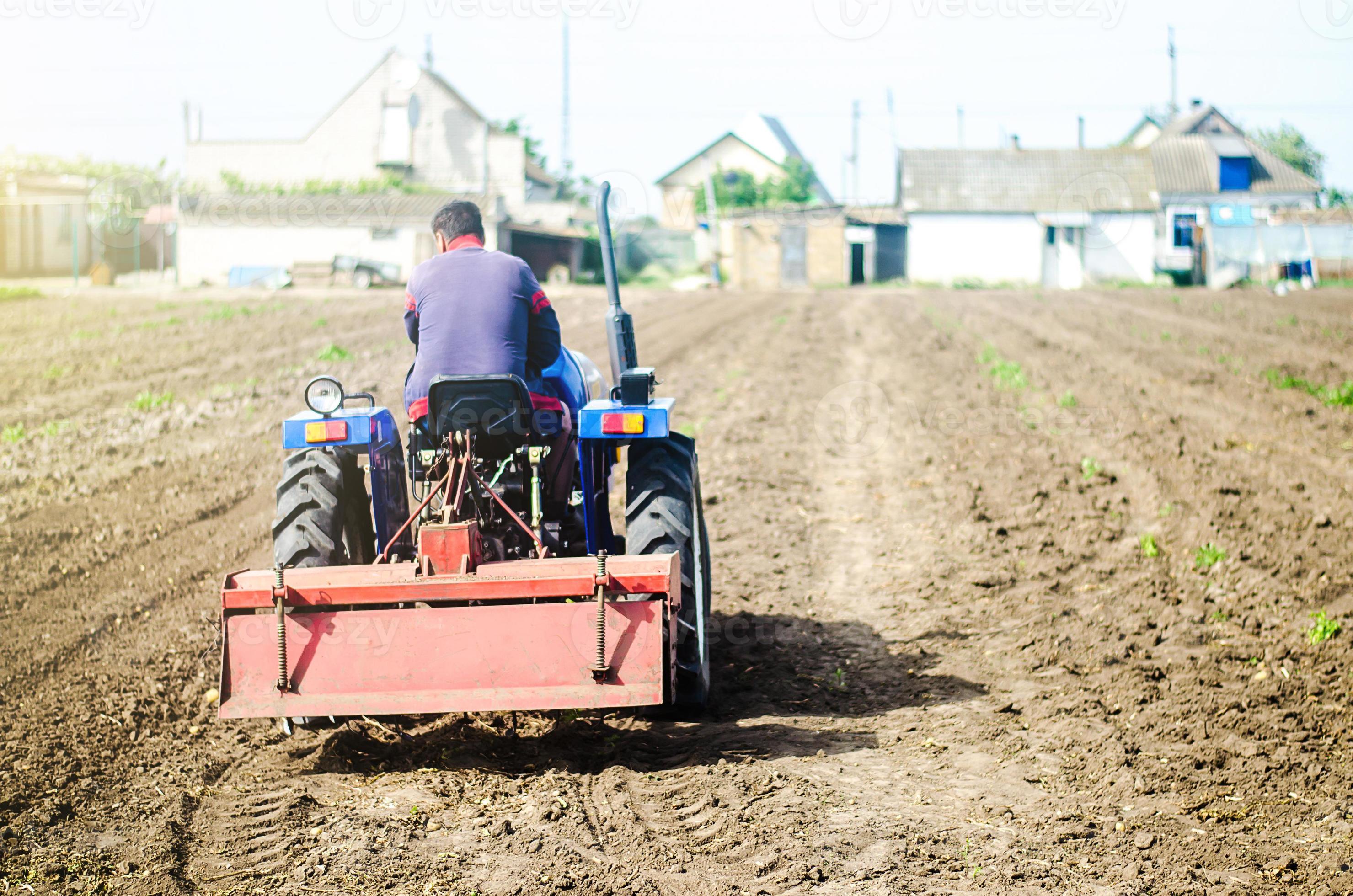 The farmer drives a tractor with a milling unit equipment. Loosening