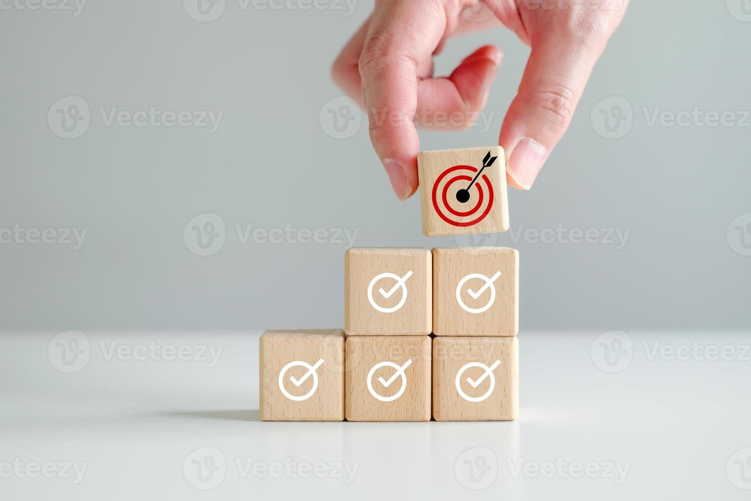 Checklist, Task list, Survey and assessment, Quality Control, Goals achievement and business success. To do list. Check mark and Hand holding dartboard from top of wooden stacks photo
