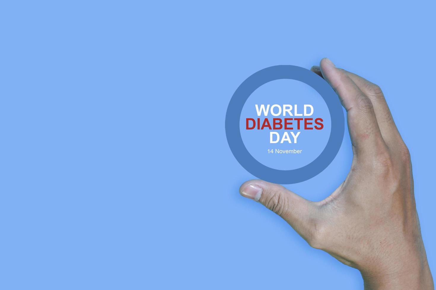 Top view inscription world diabetes day and hand gesture with red blood drop in man hands isolated on a blue background. World diabetes day, 14 november. Copy space, Health Awareness photo