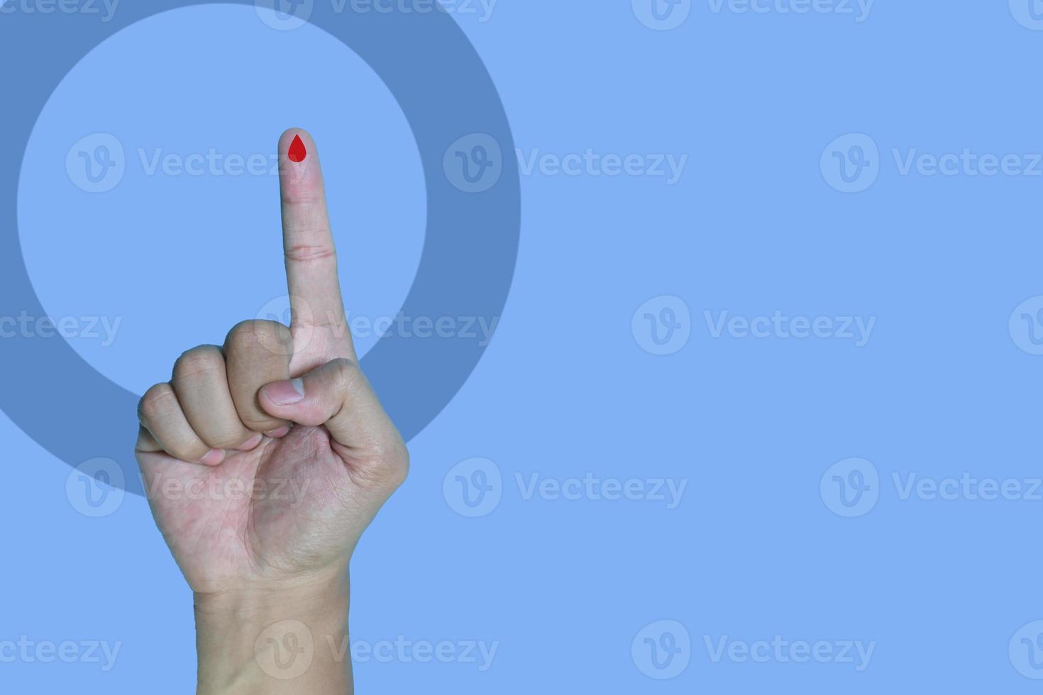 copyspace world diabetes day and hand gesture with red blood drop in man hands isolated on a blue background. 14 november photo