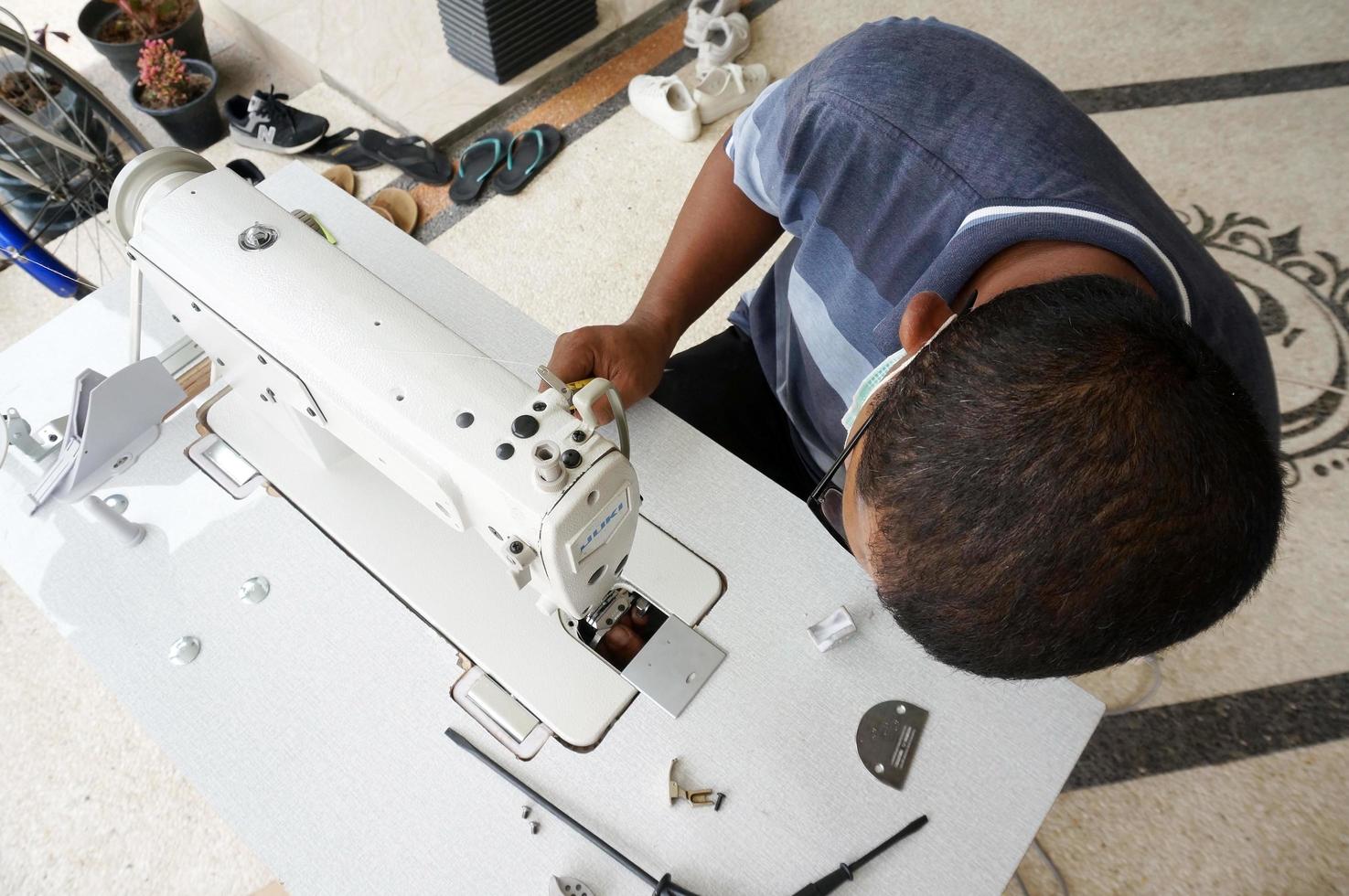 Sangatta, East Kutai, East Kalimantan, Indonesia, 2022 - an old man fixing a sewing machine, With Selective Focus photo