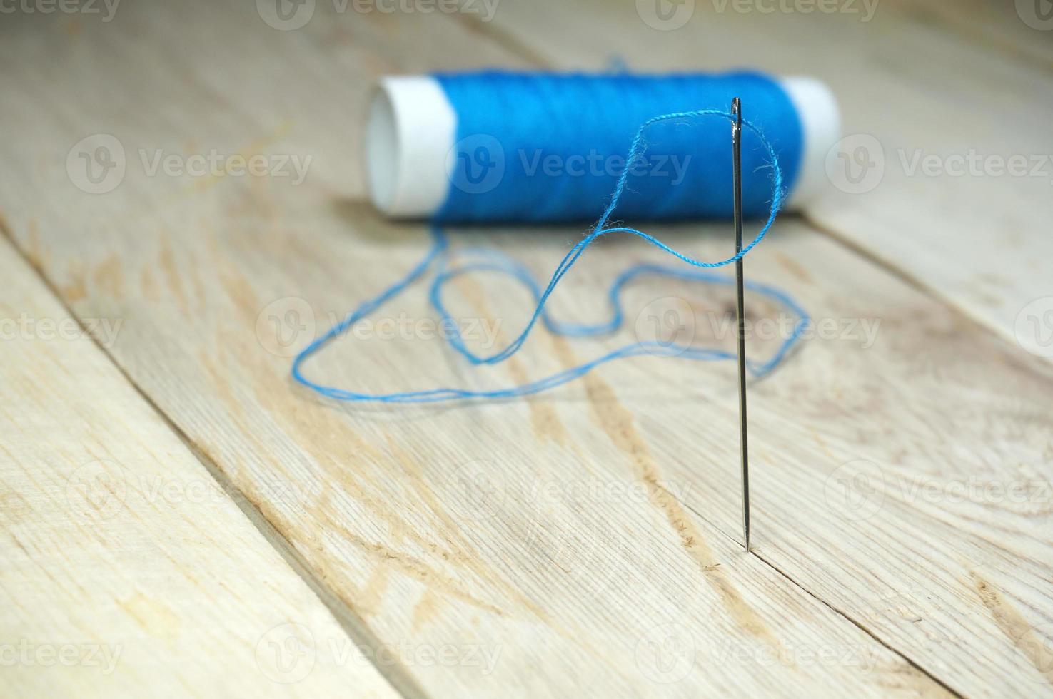 Blue threads and sewing needles on the wooden table. Selective focus to sewing needle photo