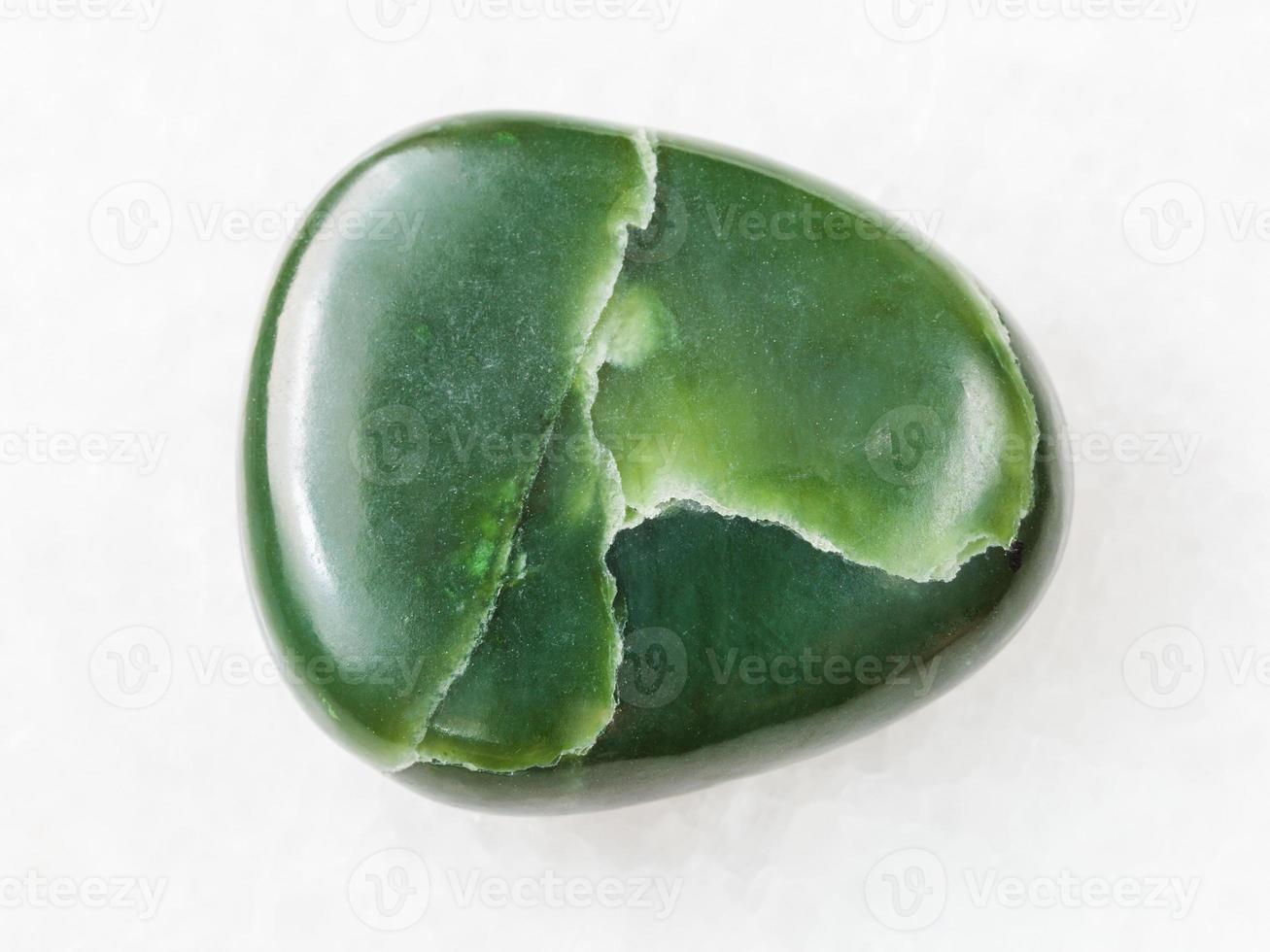 polished green nephrite gemstone on white marble photo