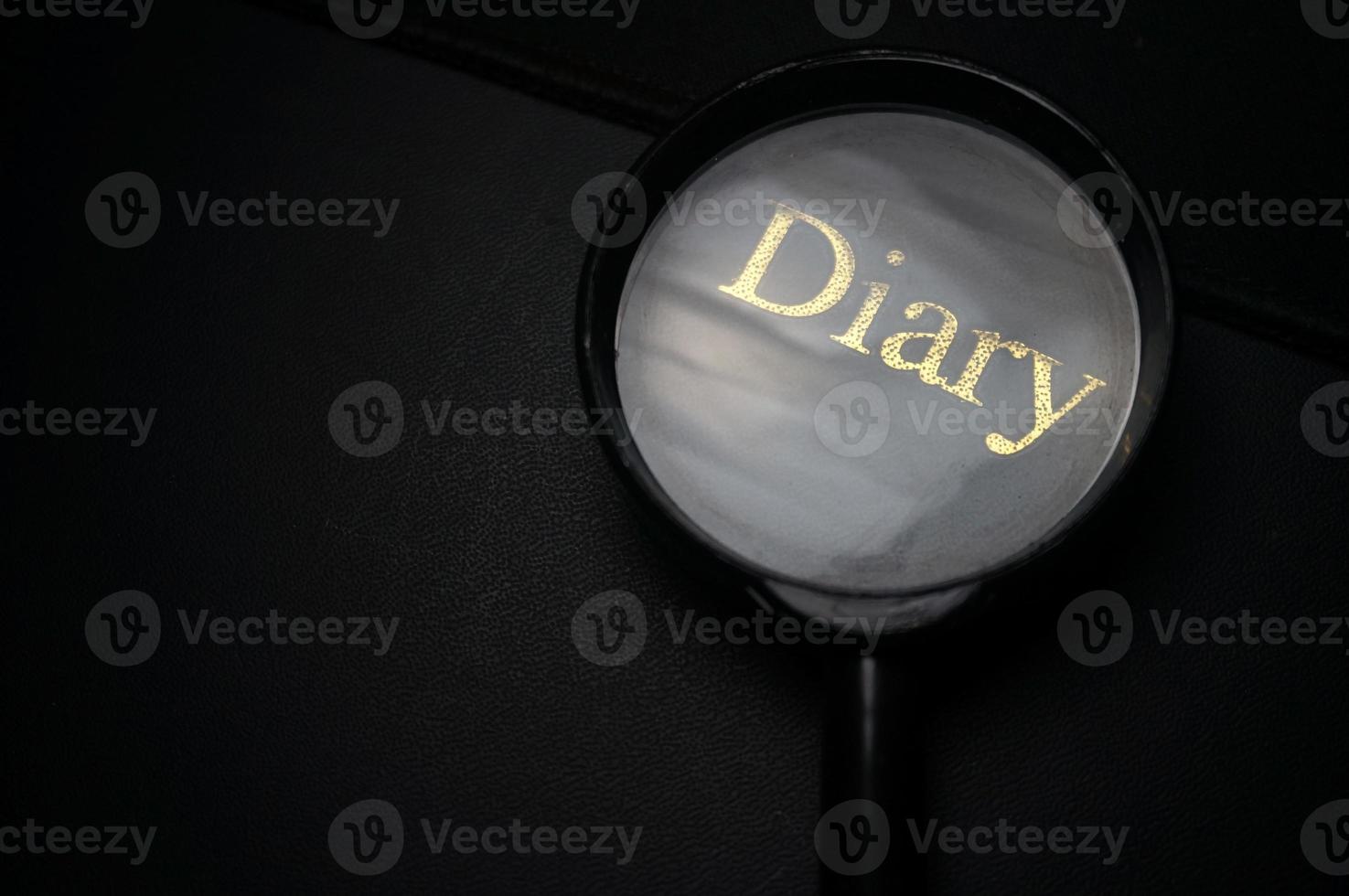 Showing DIARY Word Through Magnifying Glass. Isolated on black background. photo