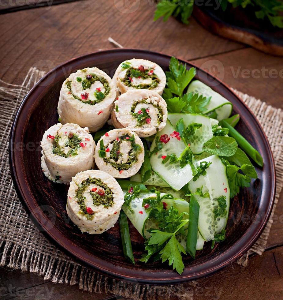 Steamed chicken rolls with greens and fresh vegetable salad on a brown plate photo